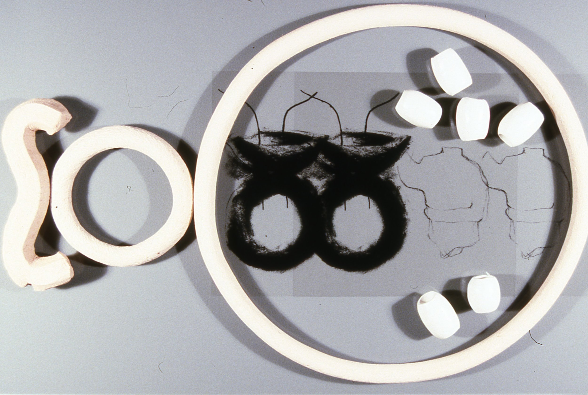Sculpture With Torsos and Canoes and 3-D Beads, Ring, and Linear Forms, KBDesrosiers, 12%22x20%22x2%22, transparencies of charcoal drawings under smoked glass and fired clay forms.jpeg