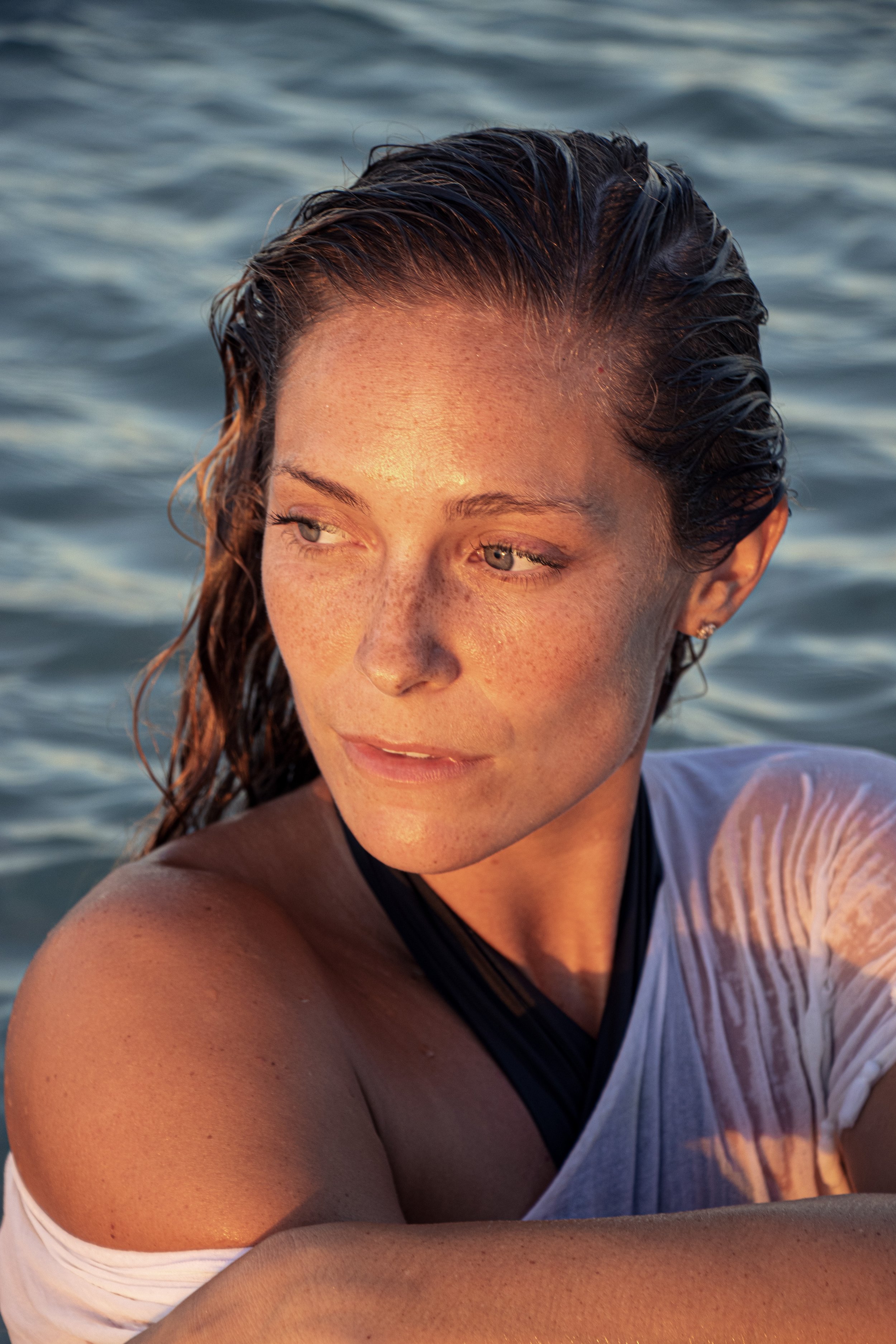 Coastal beauty portrait of model Megan Koval with wet hair in the ocean at sunset.