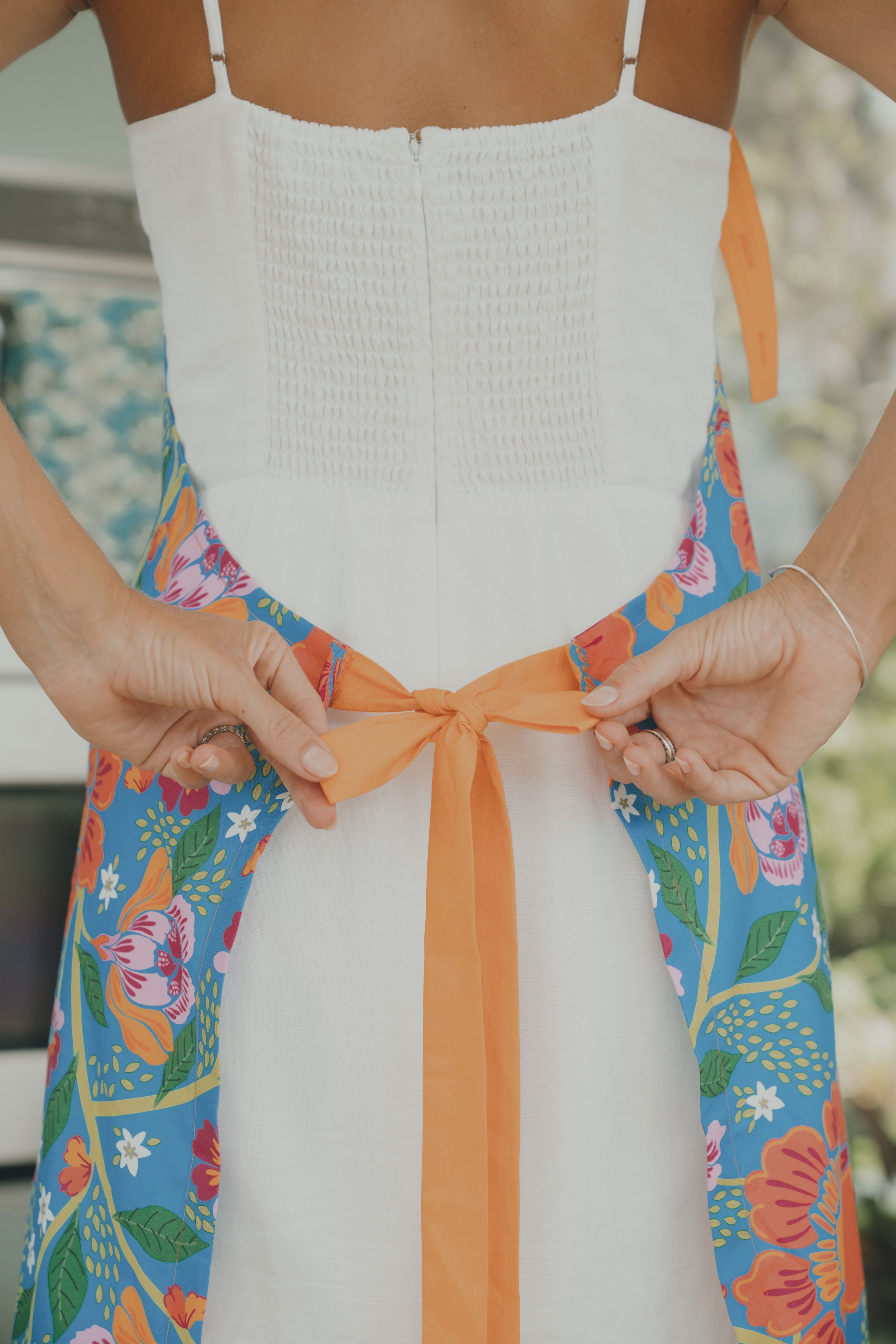 Lifestyle model tying an apron in a luxury villa kitchen, natural resort and travel lifestyle scene.