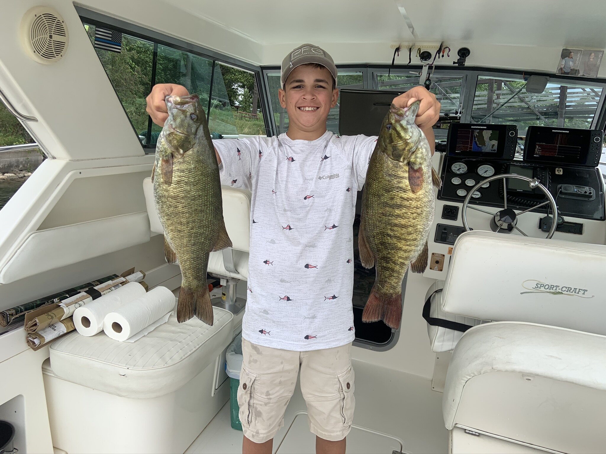 Alexandria Bay boy holding two fish on boat
