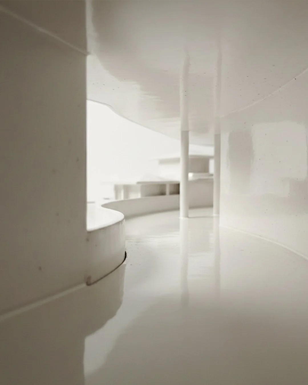 Inside a glazed scale model, a curved gallery and slender columns