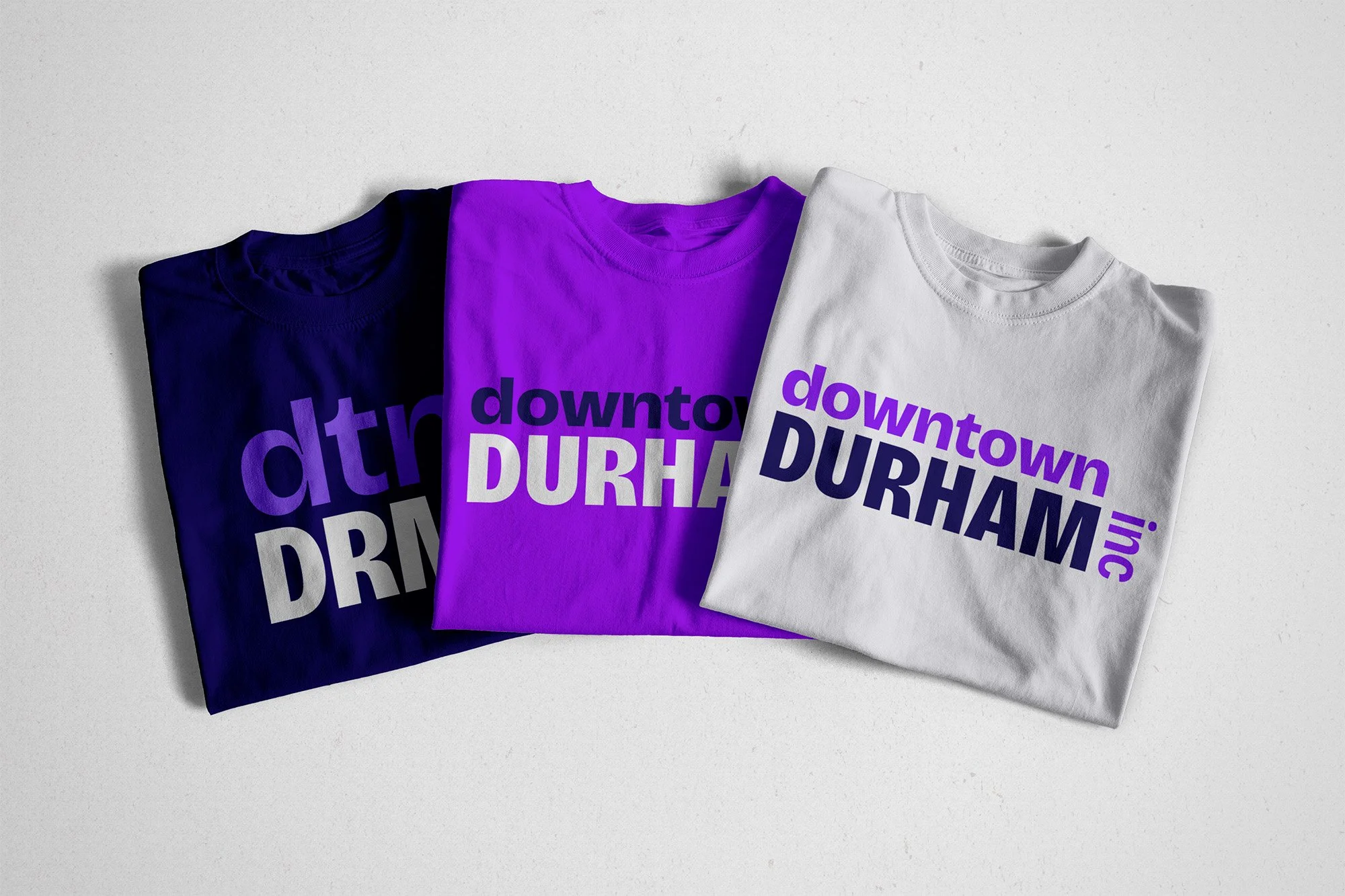 Three t-shirts, each with a different variation of the DDI logo in different colors.