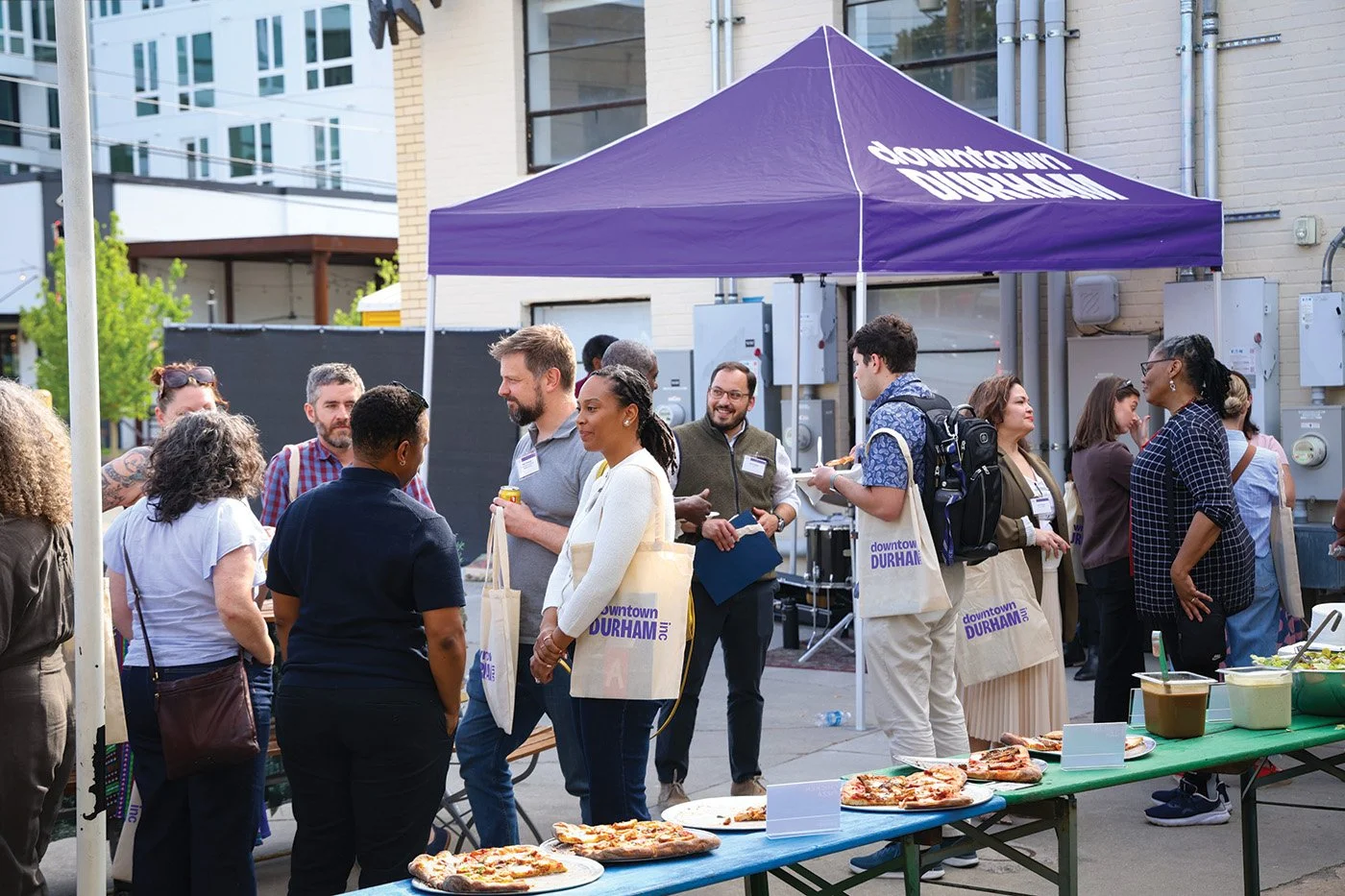 A group of people mingling outdoors at a DDI event, surrounded by DDI branding.