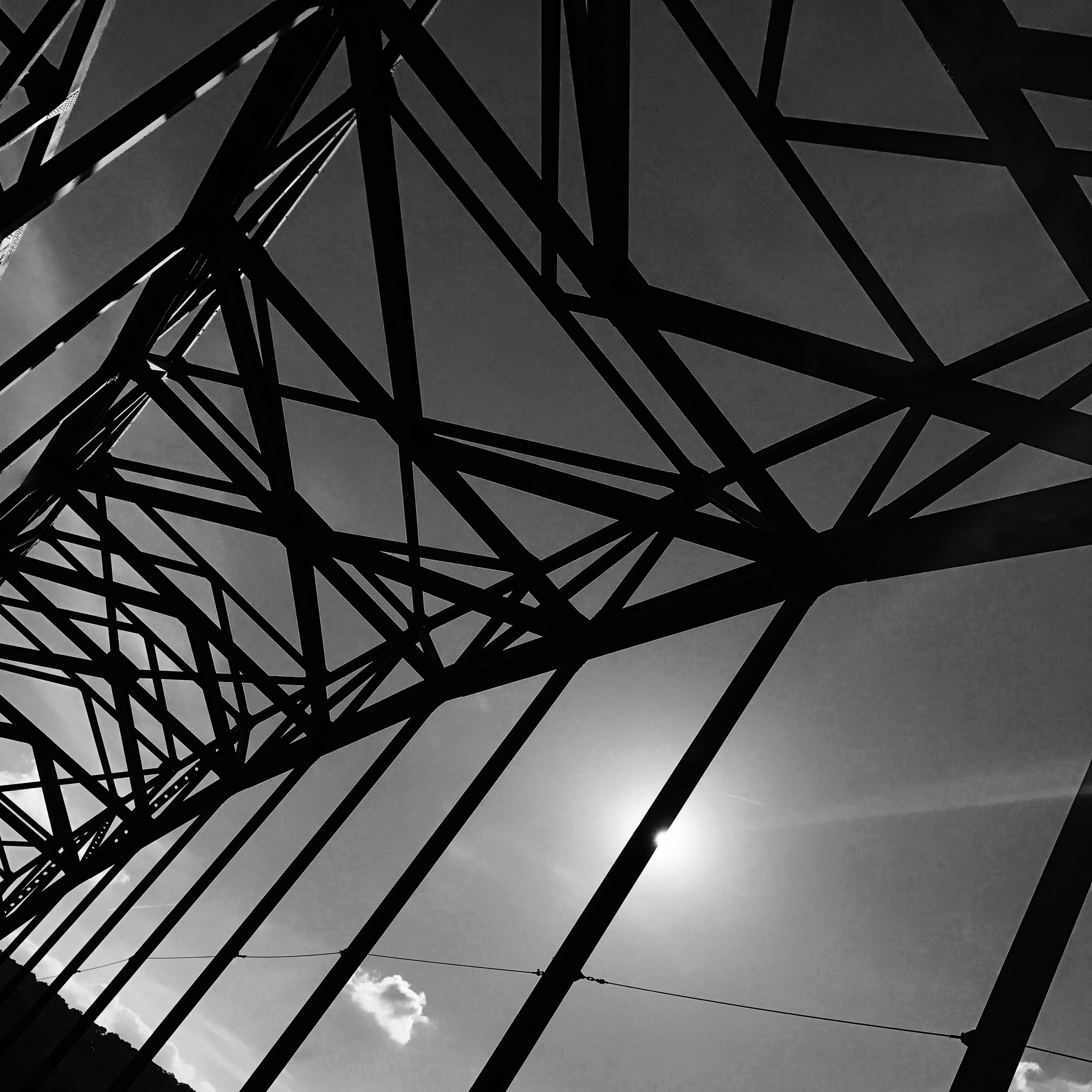 Sun behind bridge on highway.