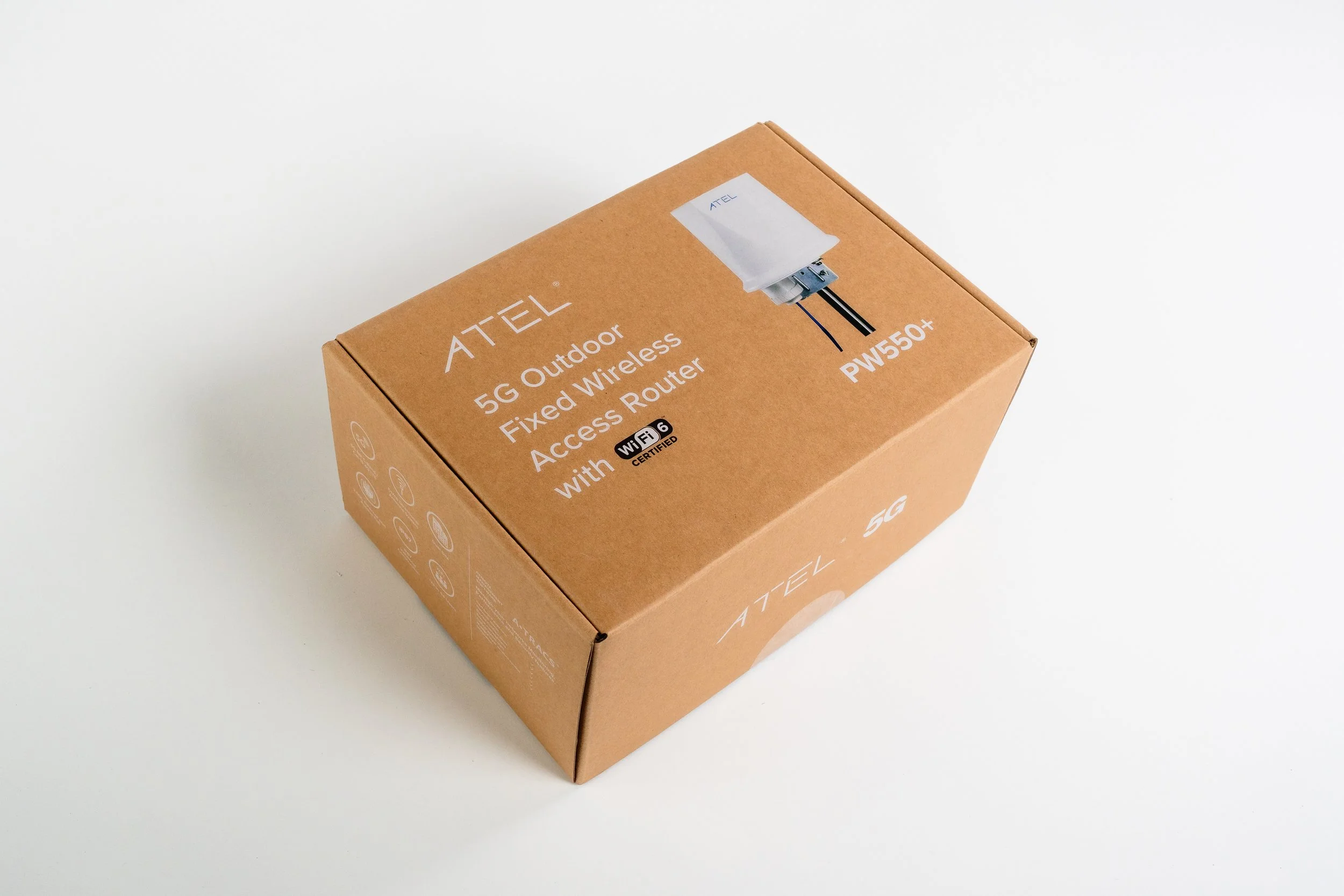 Brown cardboard box labeled ATEL 5G outdoor fixed wireless access router with Wi-Fi 6 certification on a white surface.