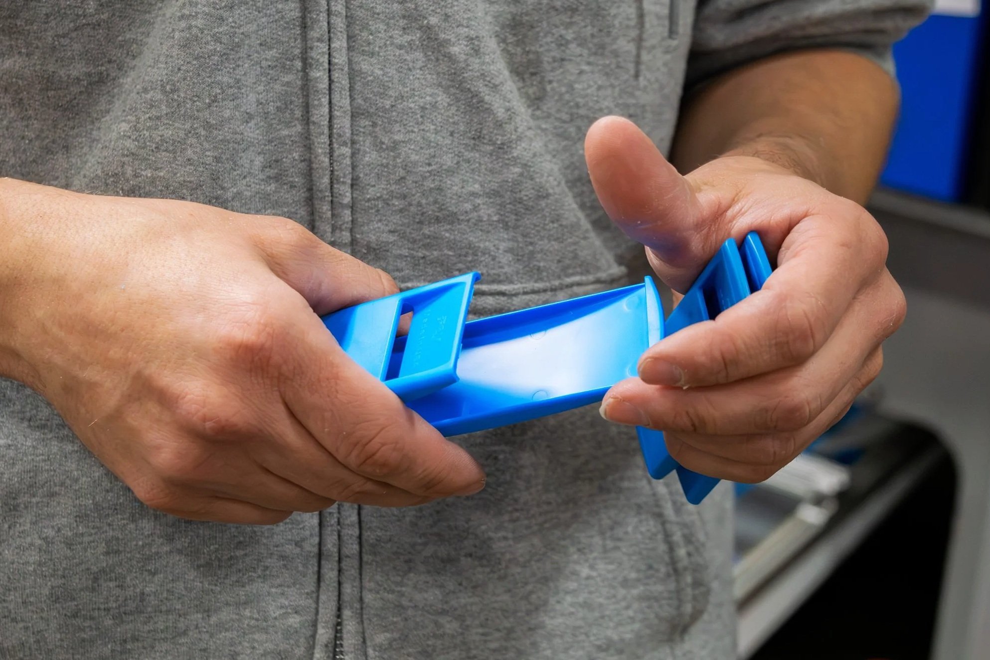 
A Fey Industries employee inspects a blue product fresh from the injection mold.