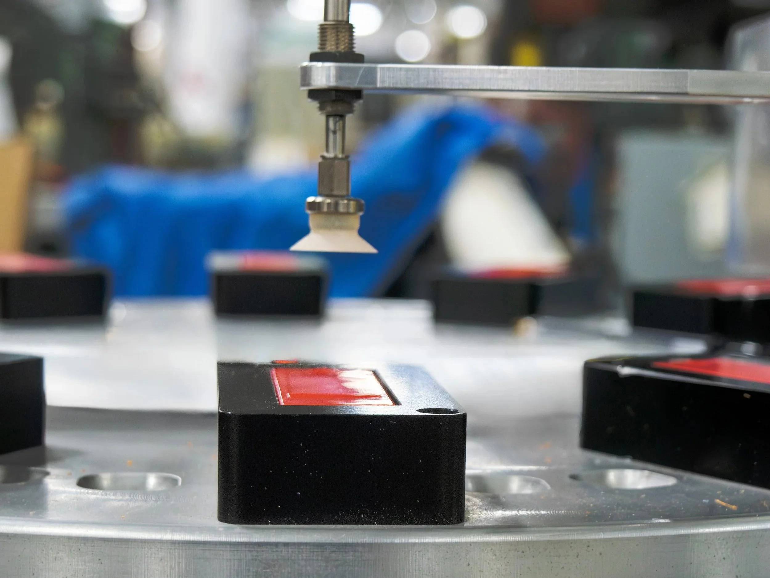 A second view of a sonic welding machine finishing a bright red product.