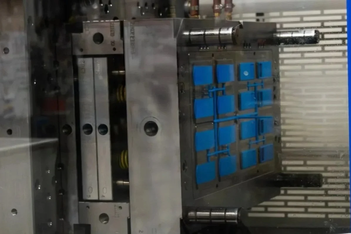 Image of an Injection Molding mold that was custom made at Fey Industries. It holds a bright blue product ready to be removed and packaged.