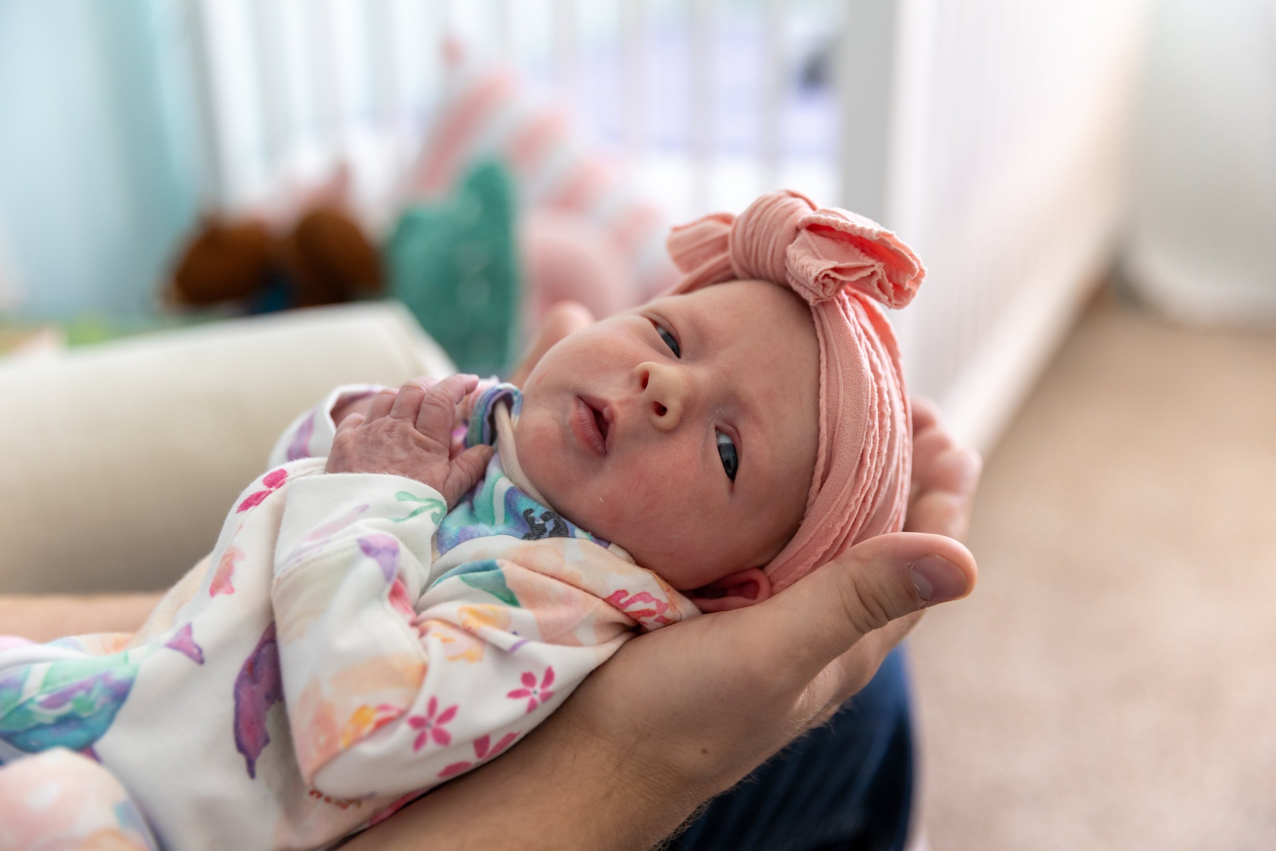 Minneapolis in-home newborn photography session - Up close image of newborn being held with their head in the dad's hands.