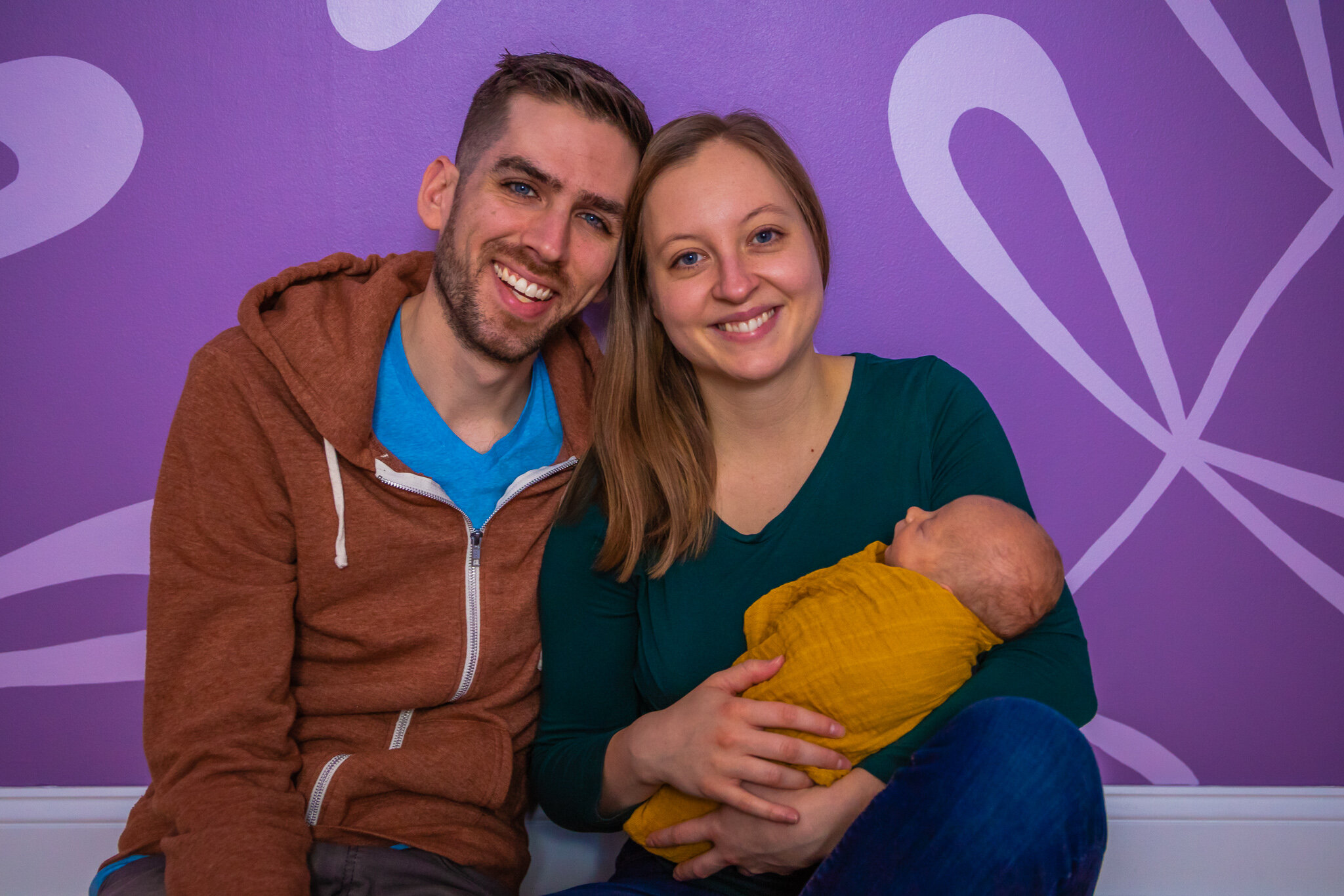 Newborn session, father and mother sitting holding baby in home nursery