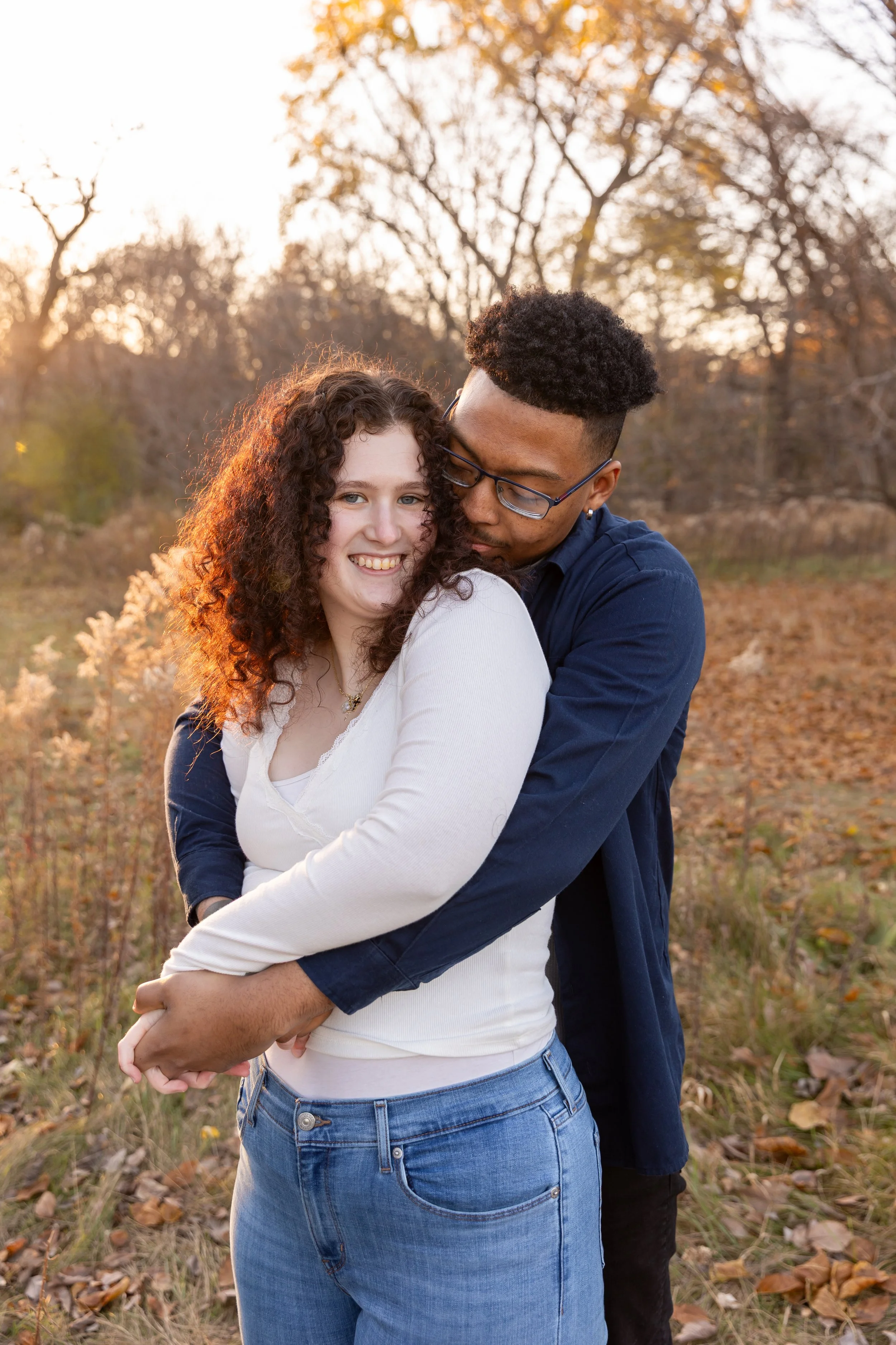 Minneapolis couples photography - A couple embrace each other with their arms around their waist while smiling at Minnehaha Falls Park in Minneapolis, MN.