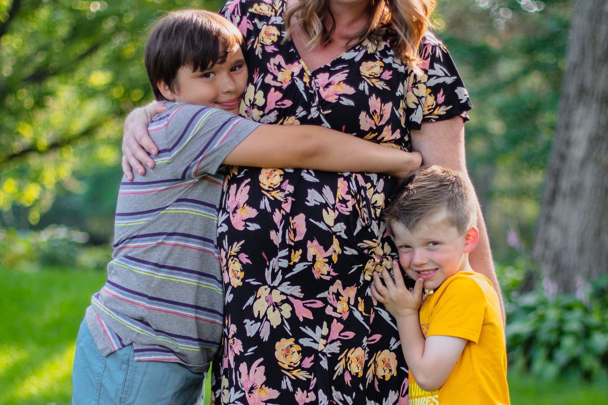 Maternity session, close up of two sons standing next to their mother hugging her baby bump
