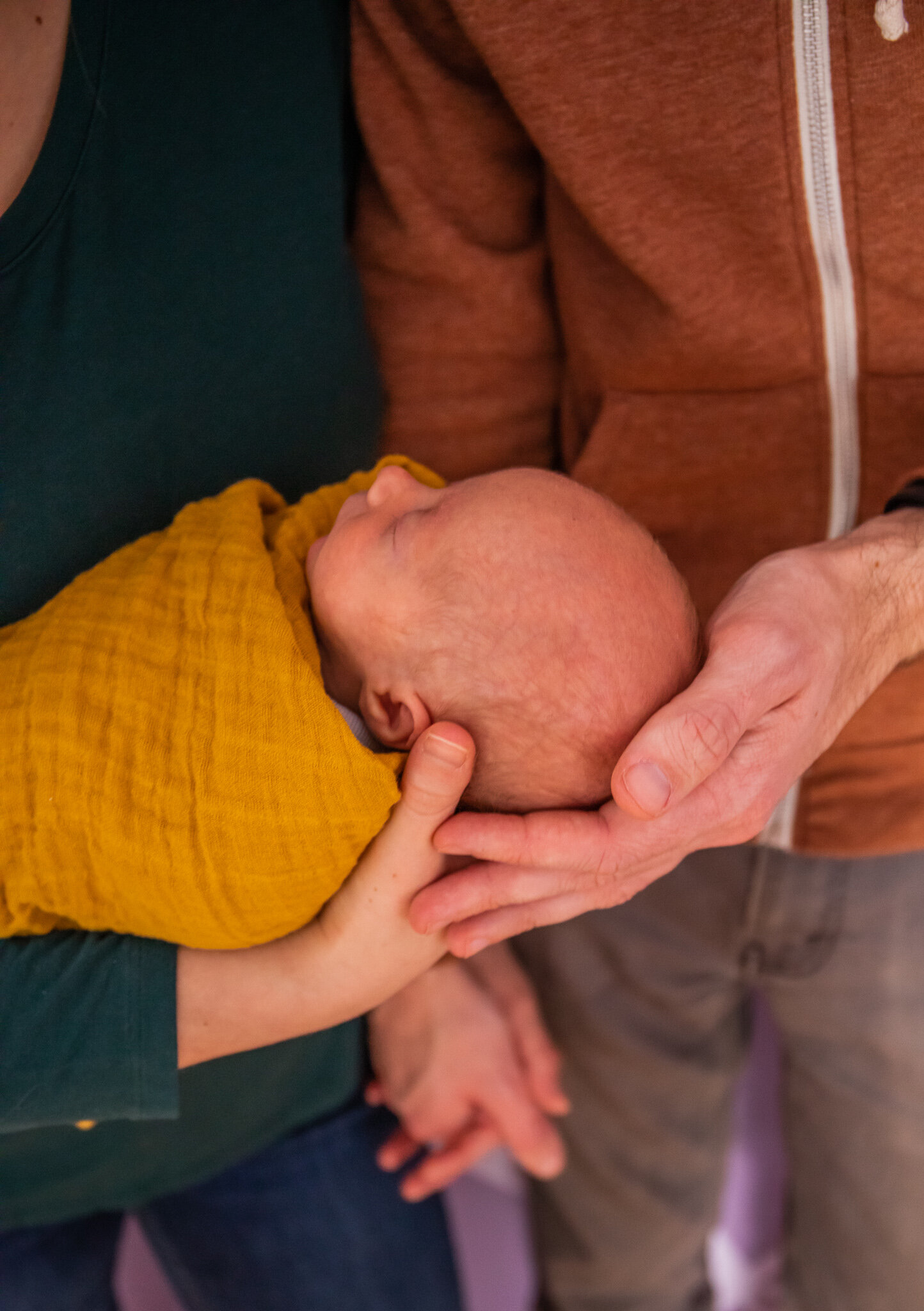 Newborn session, close up of father and mother holding baby in home nursery