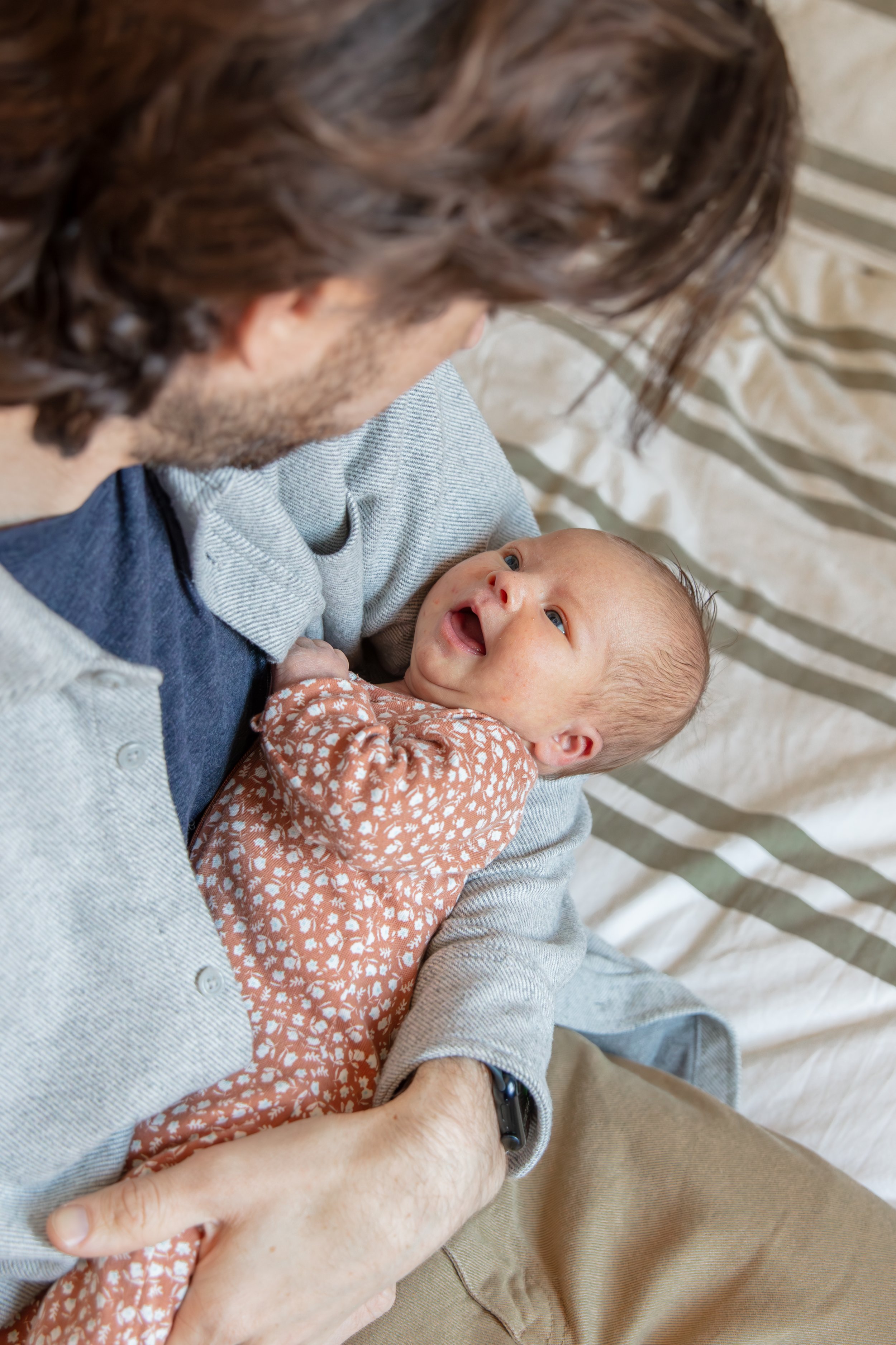 Close up over the father's shoulders of baby looking up at him smiling.