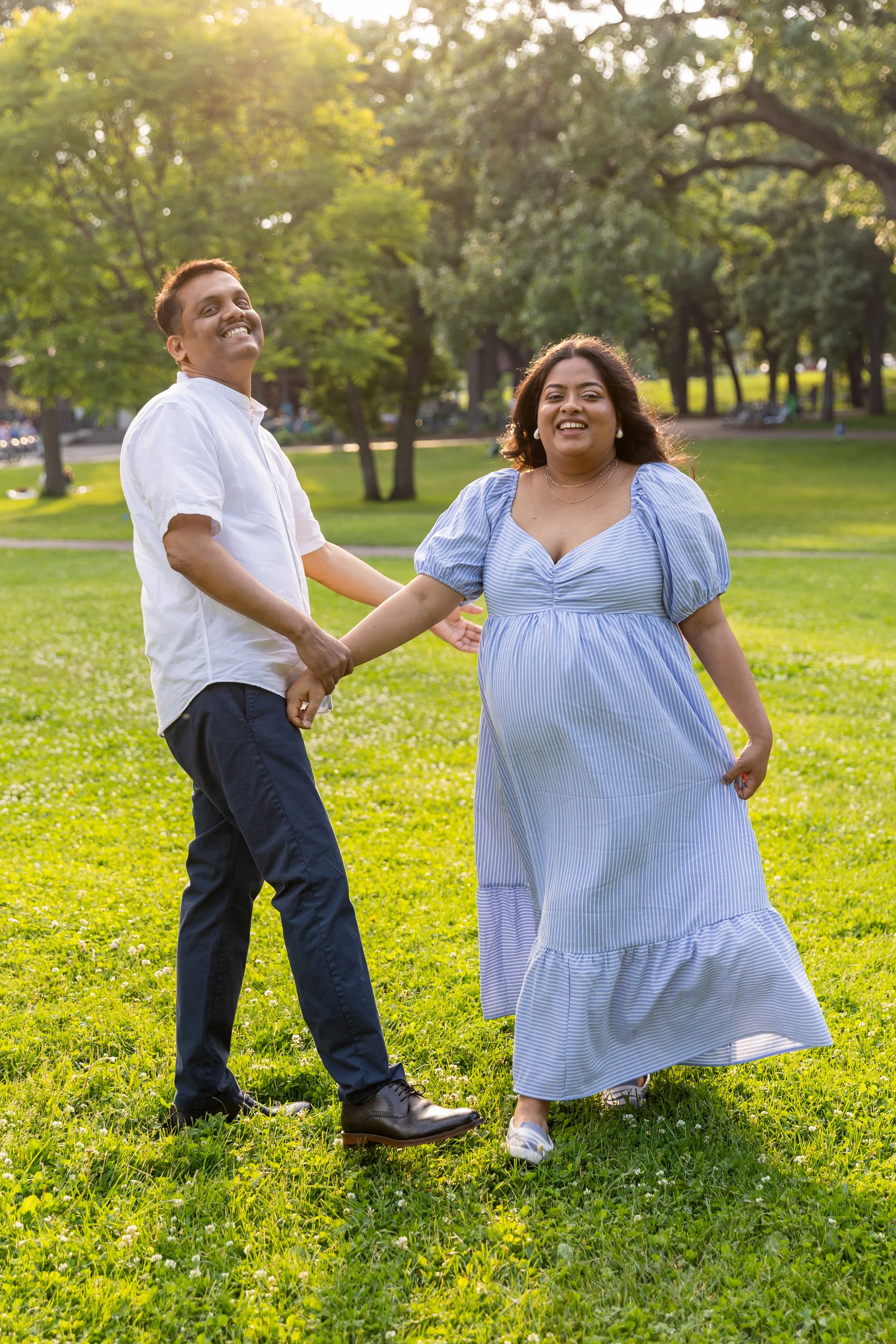 Maternity session - father and mother dance and swirl around together smiling at the camera while holding hands at Minnehaha Falls Park 