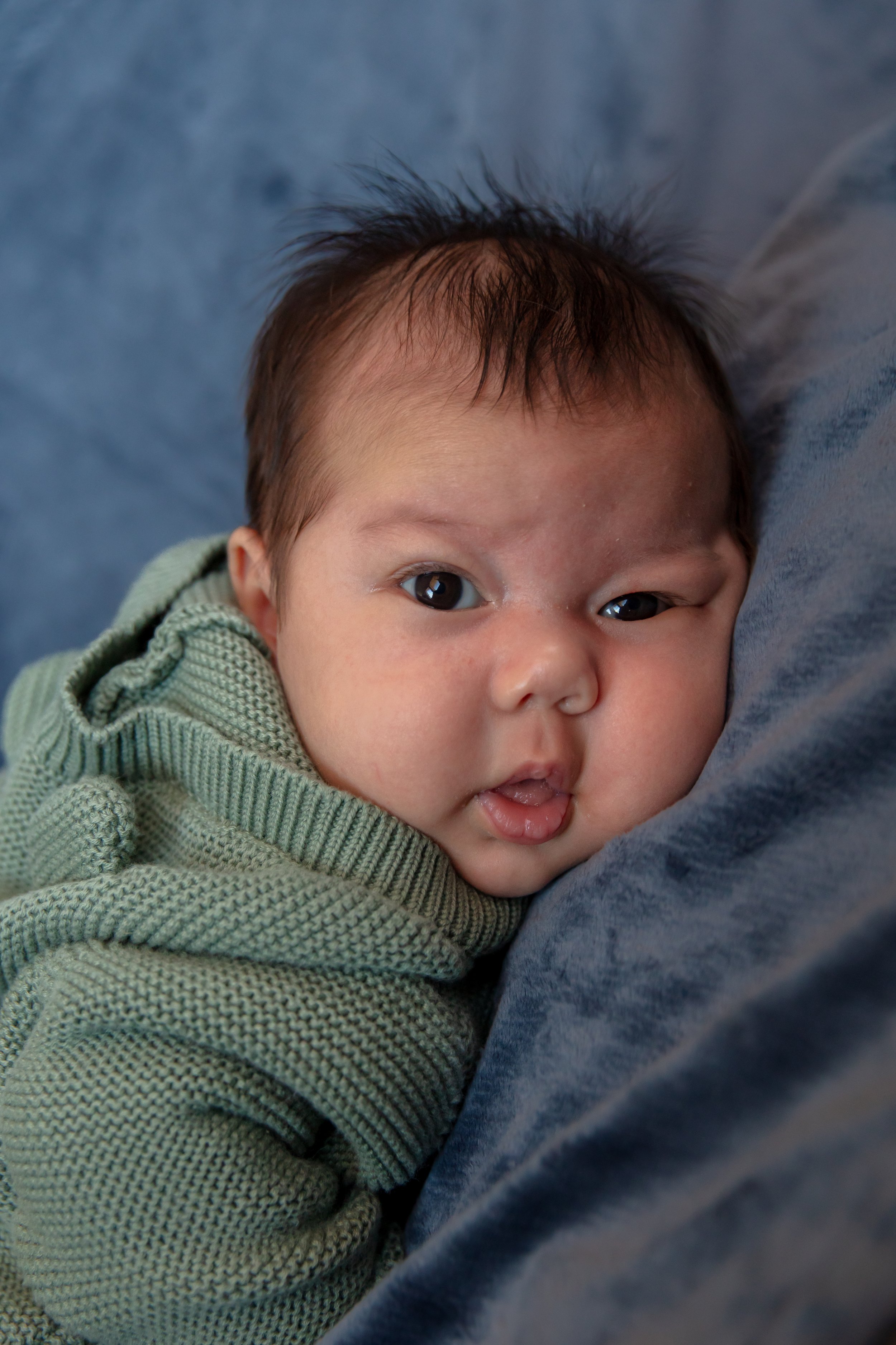 Close up of baby looking at the camera while laying on a blanket.