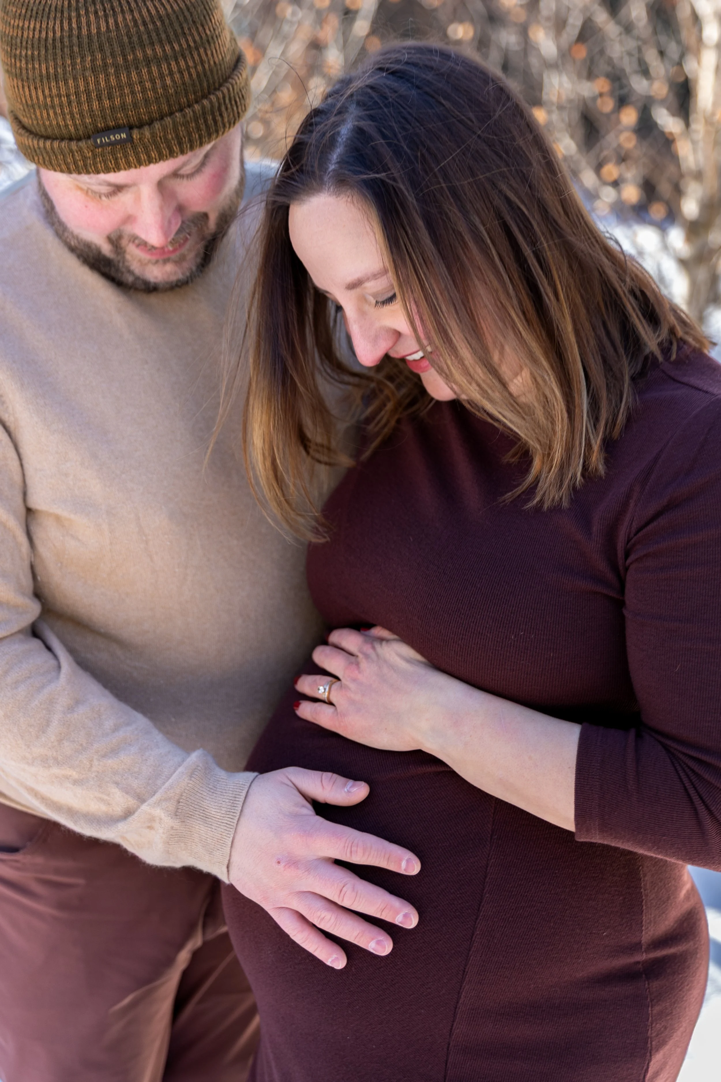 Minneapolis maternity photography session - close up of father and mother standing together cradling and looking at the baby bump while at Arneson Acres Park in Edina, MN in the winter.