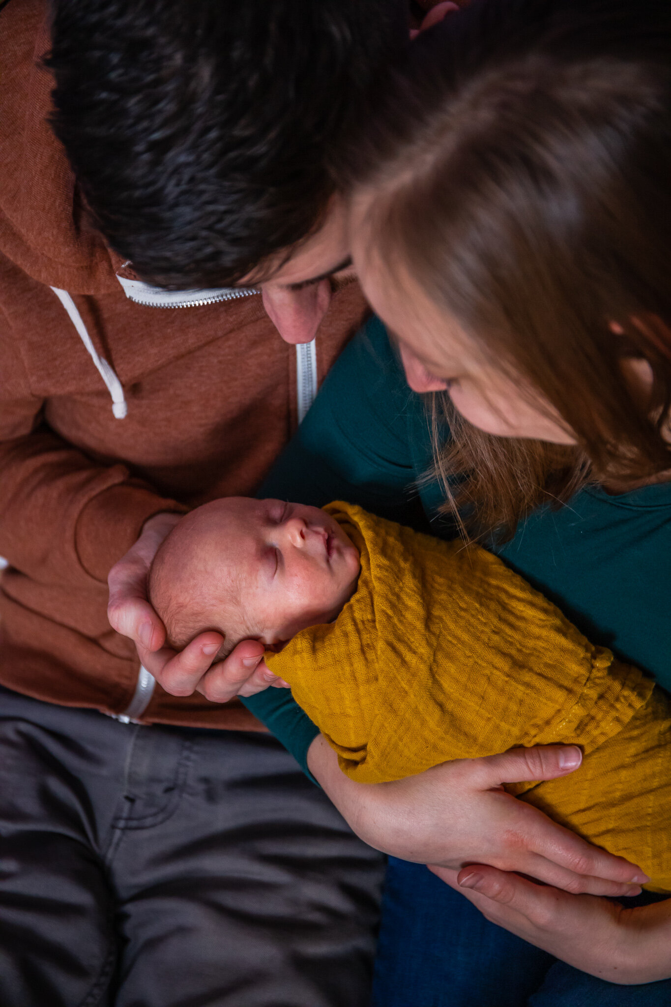 Newborn session, close up of father and mother sitting holding baby in home nursery