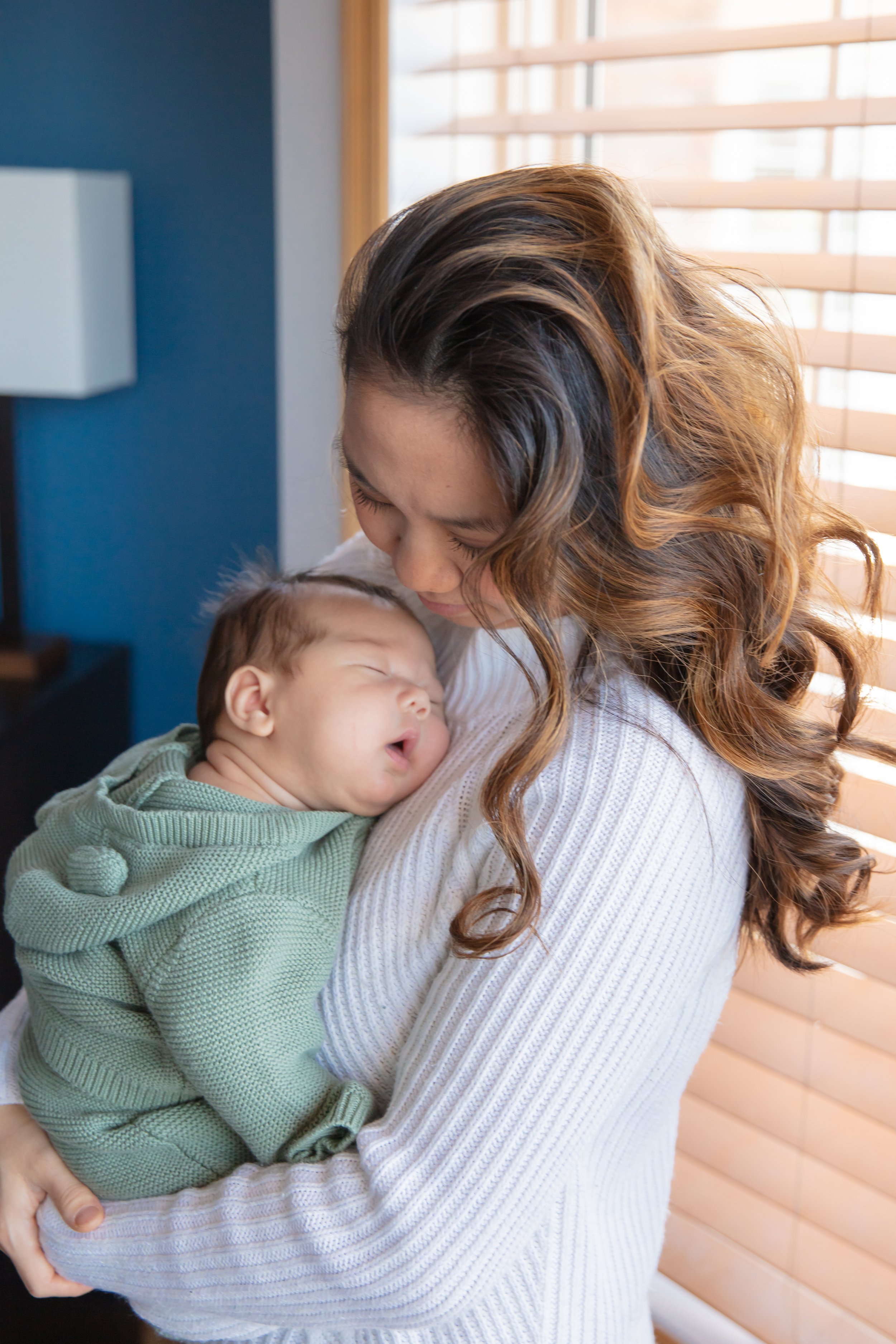 Mom holds her baby in her arms as she smiles down at her baby.