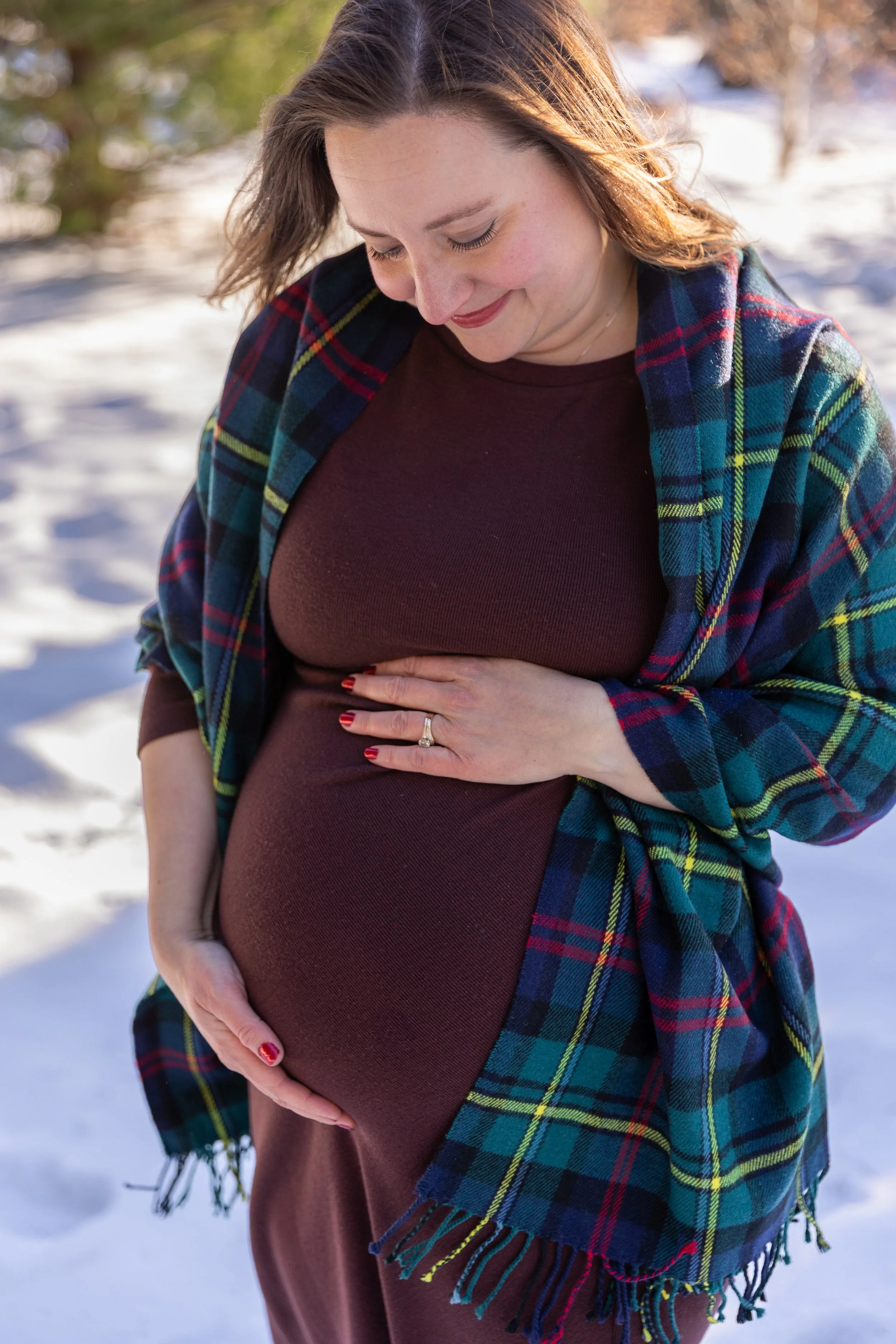 Minneapolis Maternity session, up close of an expecting mother cradling her baby bump smiling down at the bump while wearing a blanket at Arneson Acres Park in Edina, MN in the winter.