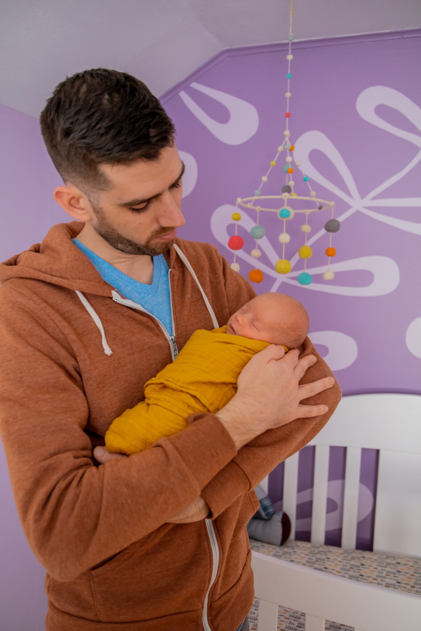 Newborn session, baby asleep in father's arms in home nursery