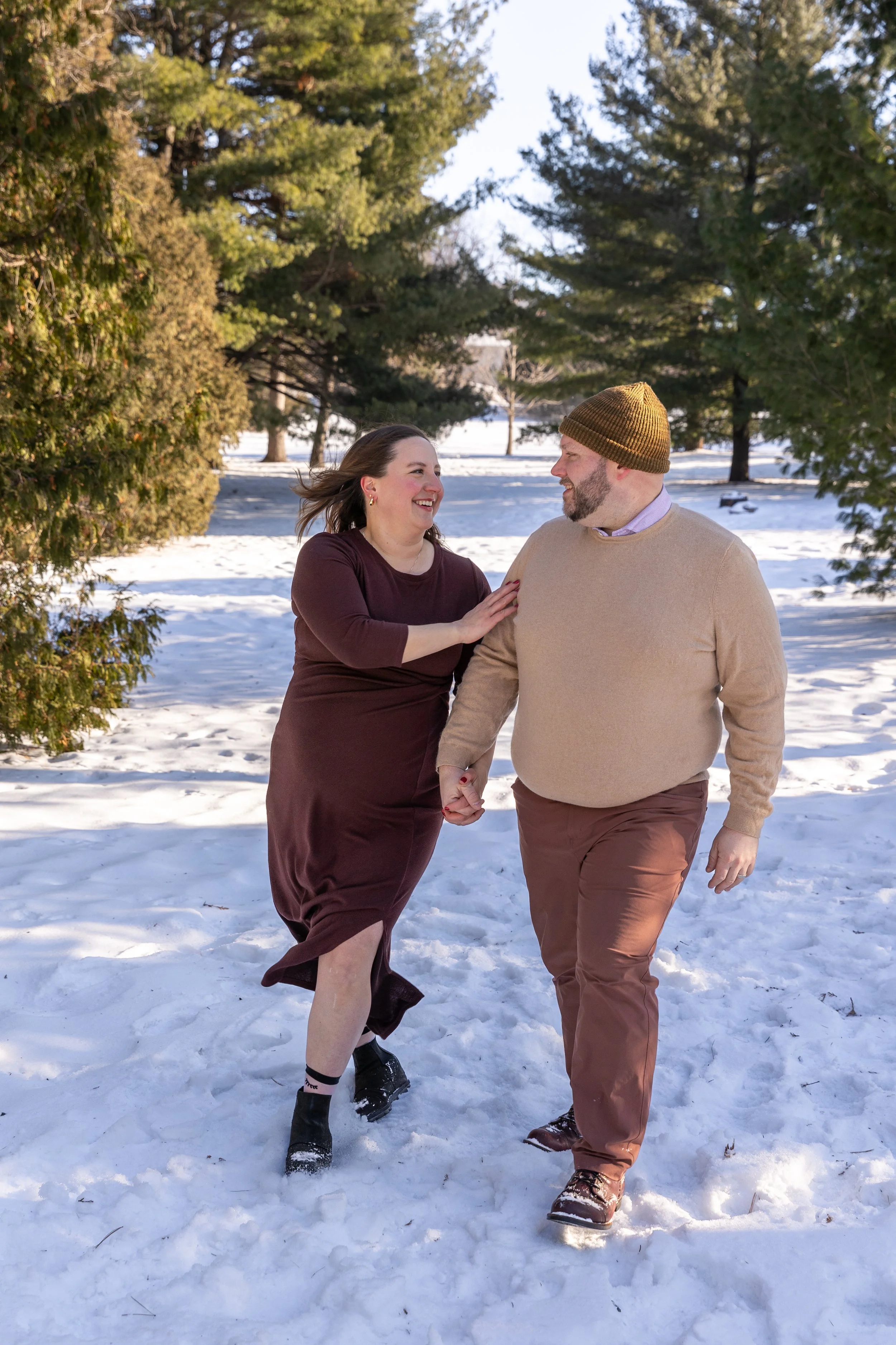 Minneapolis Maternity photography session - A soon to be mother and father walk towards the camera holding hands while smiling at each other at Arneson Acres Park in Edina, MN in the winter.