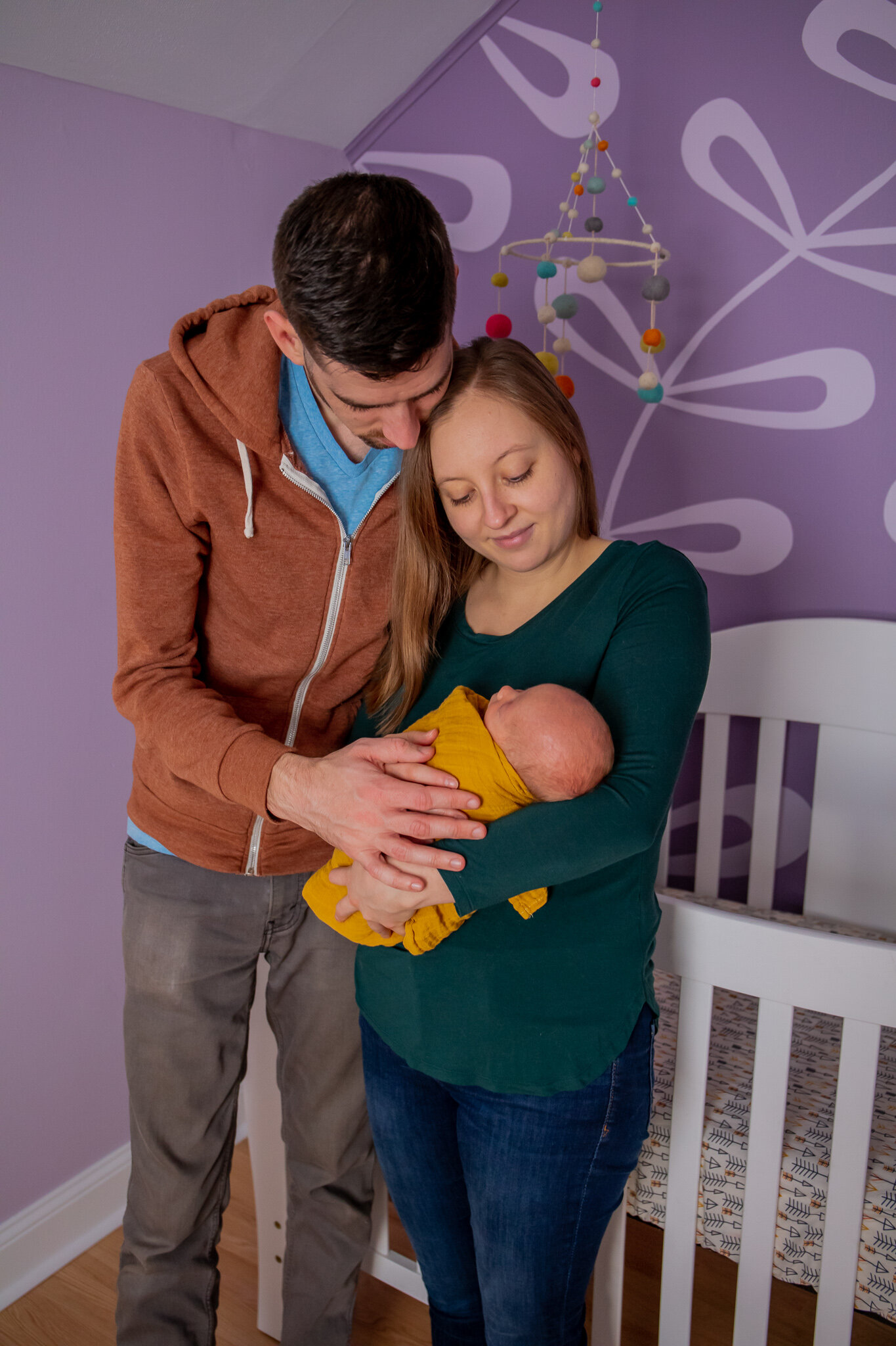 Newborn session, father and mother standing holding baby in home nursery
