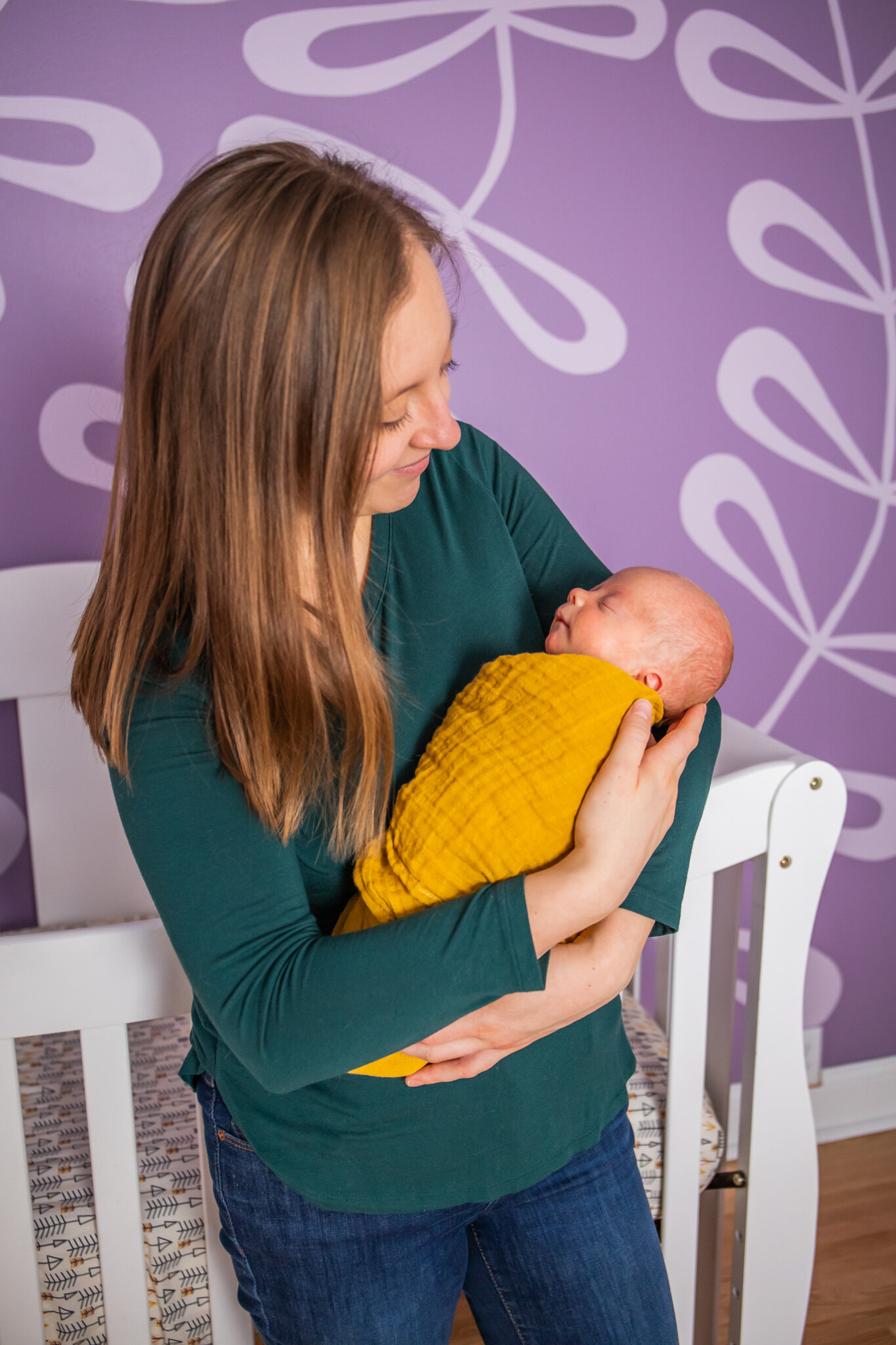 Newborn session, baby asleep in mother's arms in home nursery