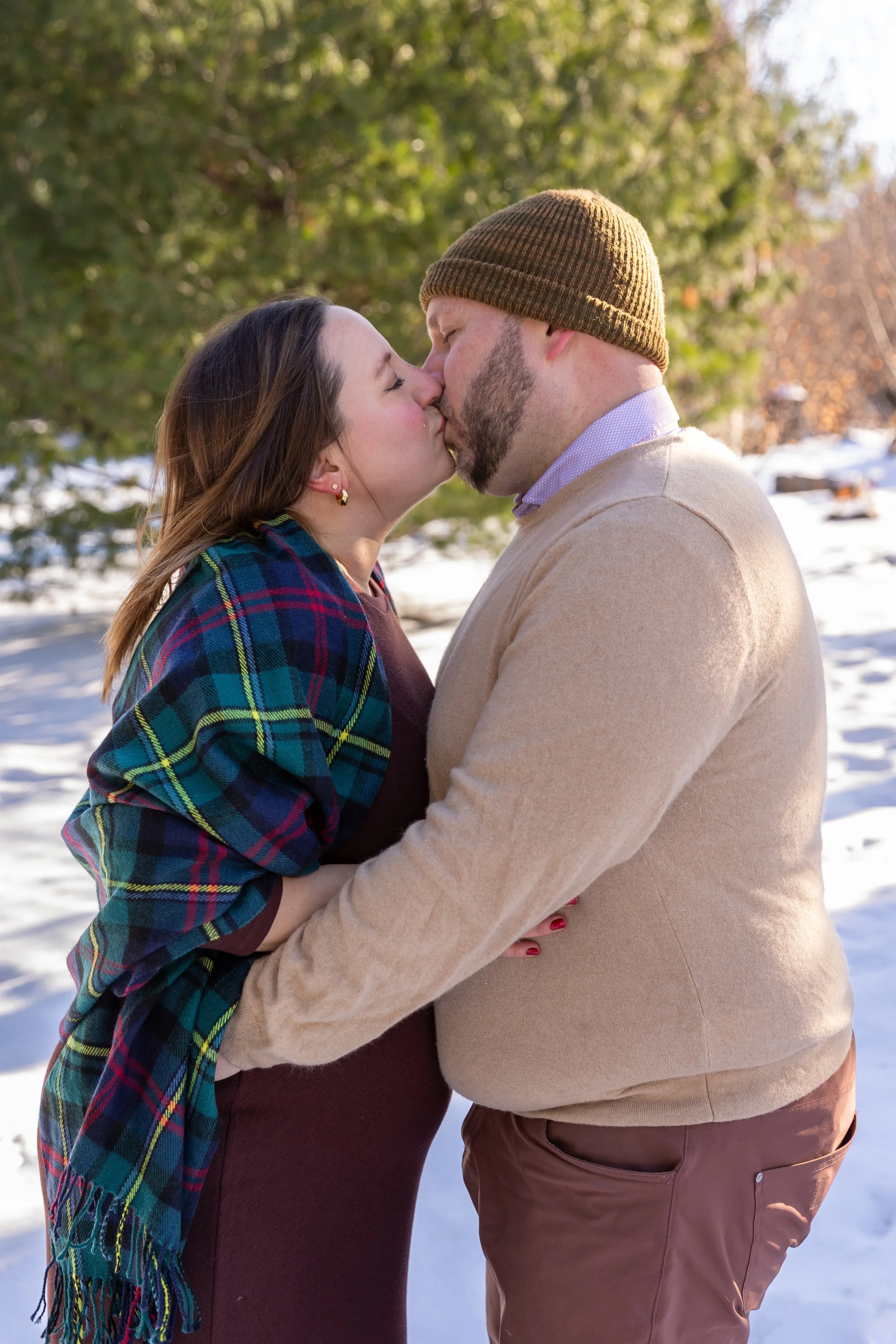 Maternity session, expecting mother and father-to-be embrace each other and kissing while at Arneson Acres Park in Edina, MN in the winter.
