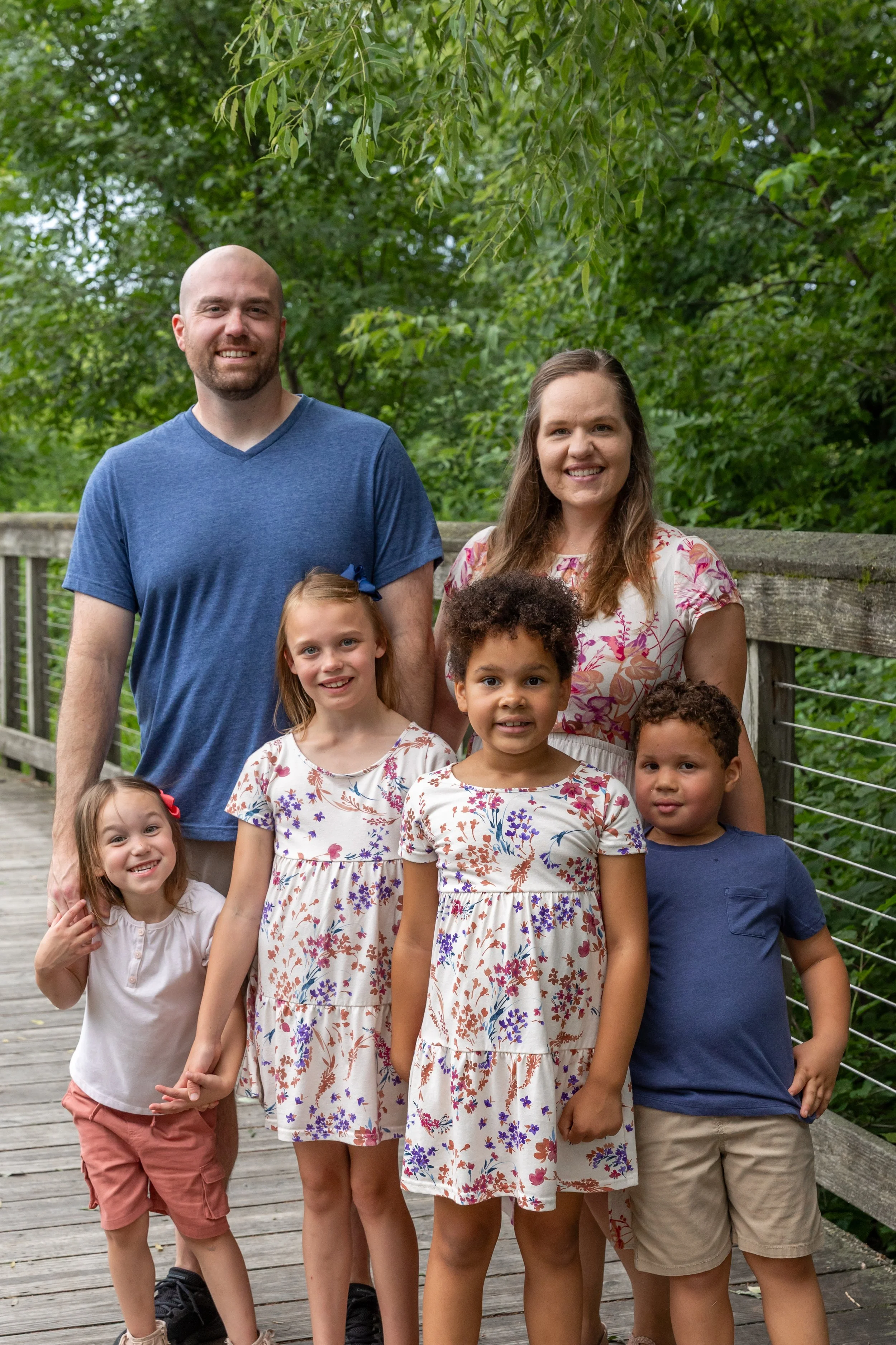 Minneapolis Family Photography - A blended family of a mom, dad and four kids stand together smiling at the camera on a bridge at Lebanon Hills Regional Park in Eagan, MN. 