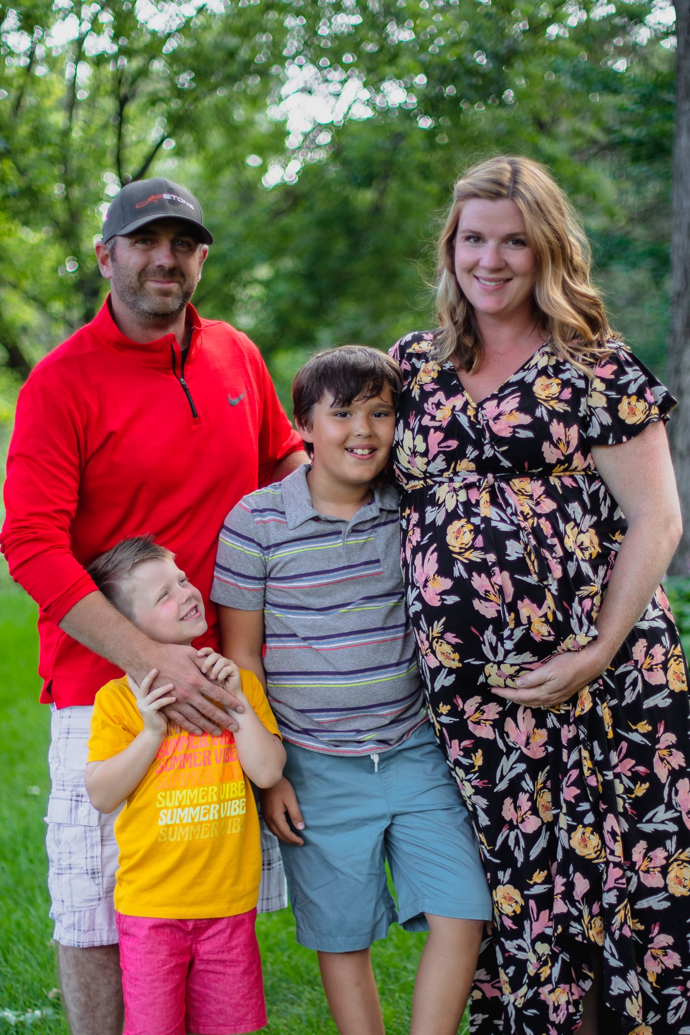 Maternity session, father and mother standing next to two sons while holding baby bump