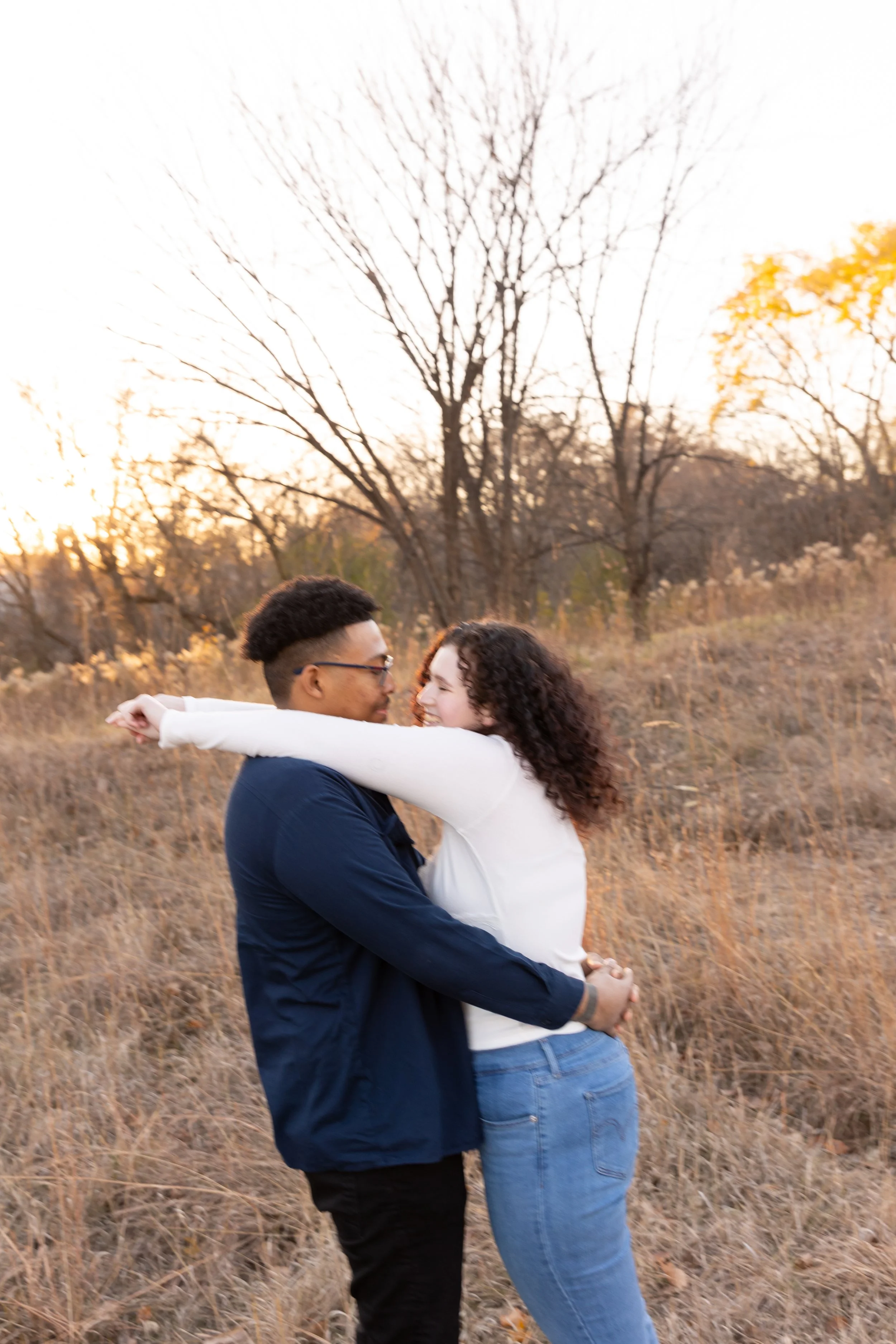 Minneapolis couples photography - A couple embrace each other with their arms around their waist while smiling at each other at Minnehaha Falls Park in Minneapolis, MN.
