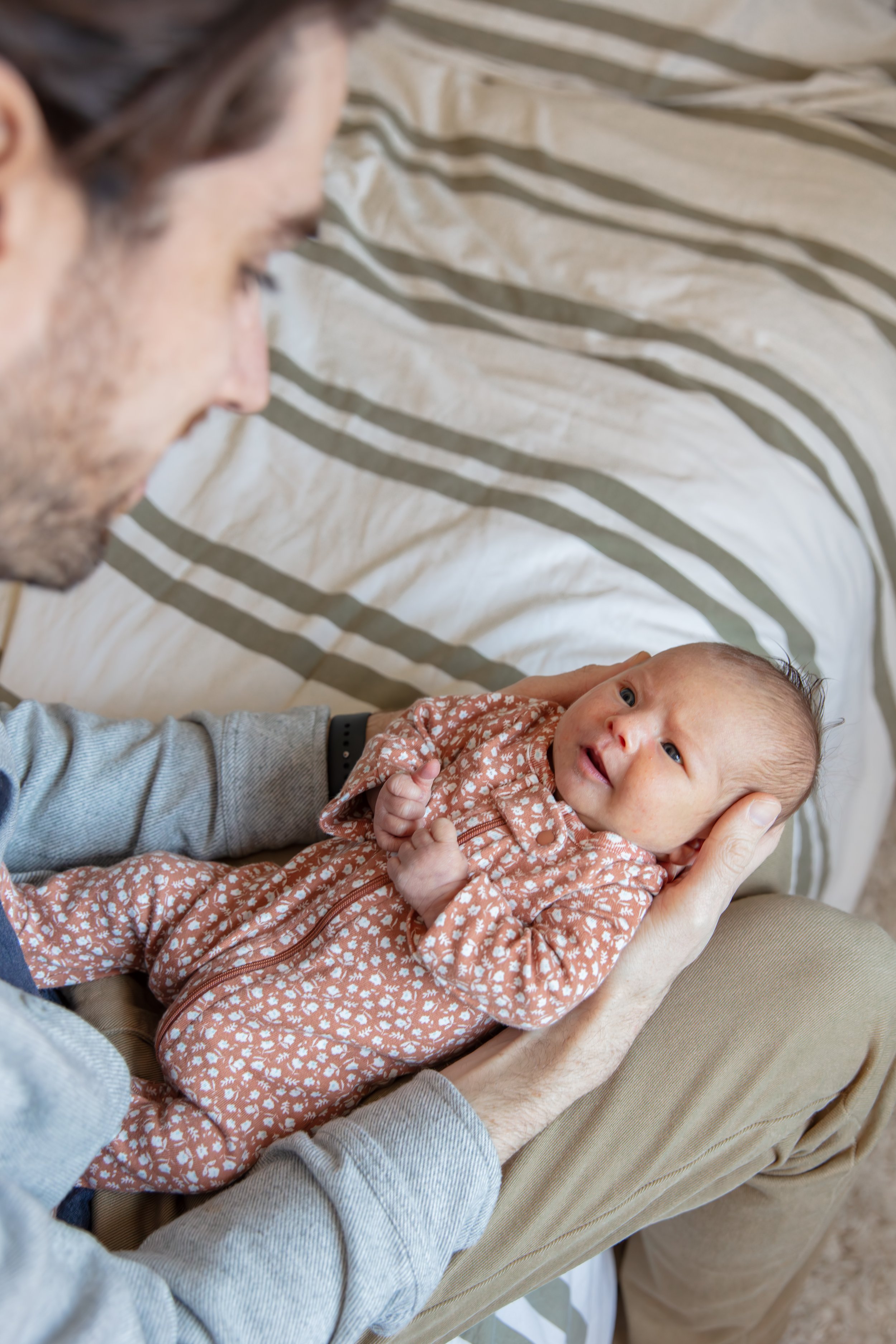 Close up over the father's shoulders of baby looking up at him smiling.