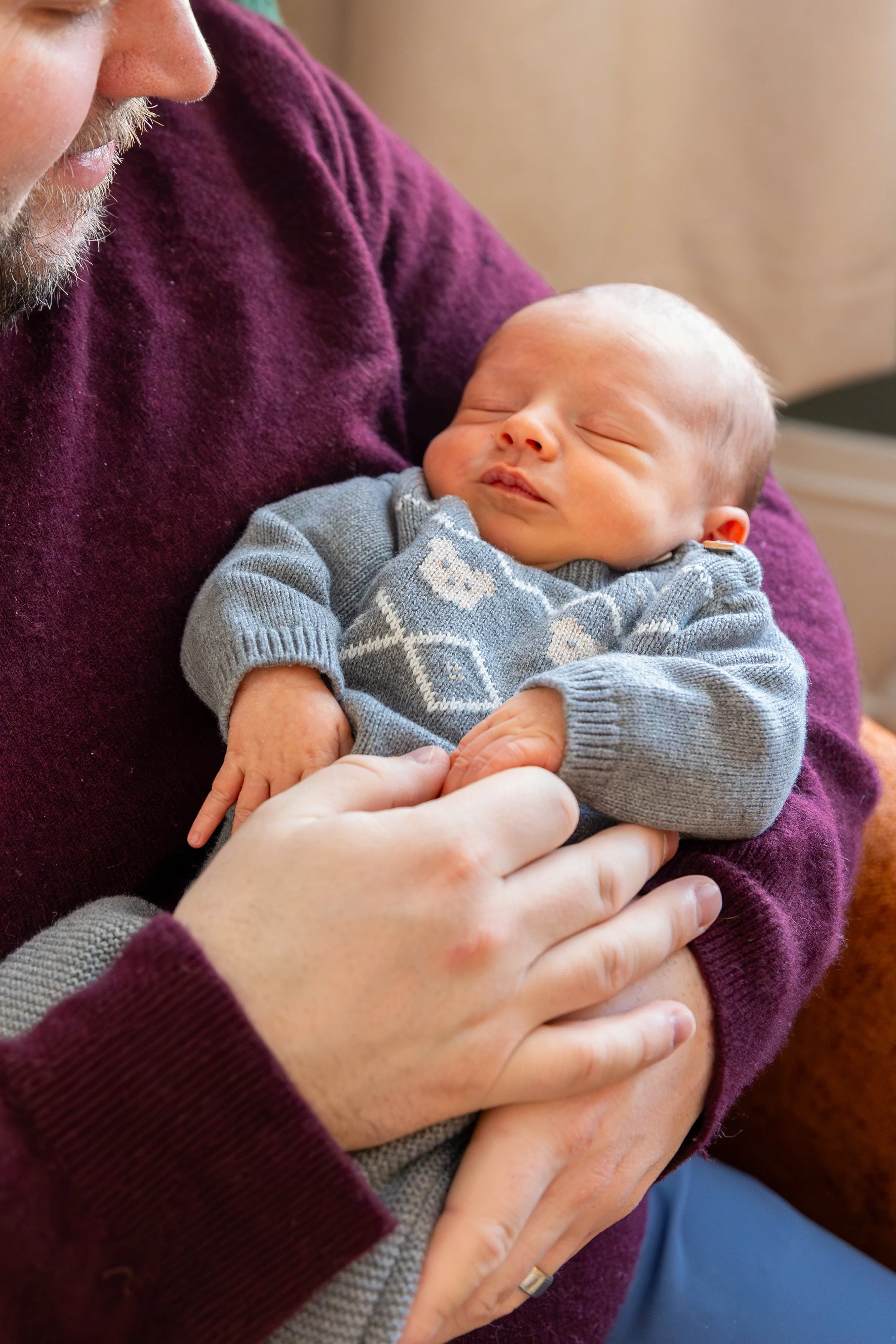 Minneapolis in-home newborn photography session - Up close image of baby being held in dads arms with him looking down at the baby. 