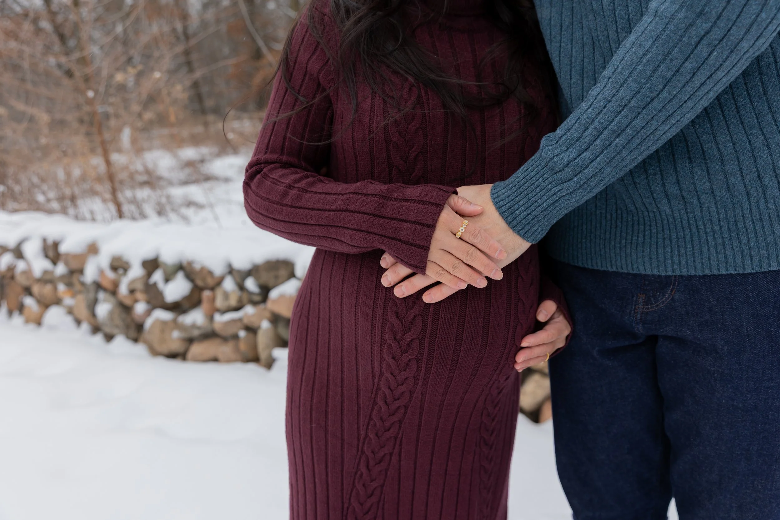 Minneapolis maternity photography session - close up of father and mother standing together cradling the baby bump while at Minnetonka Mills Park in Hopkins, MN in the winter.