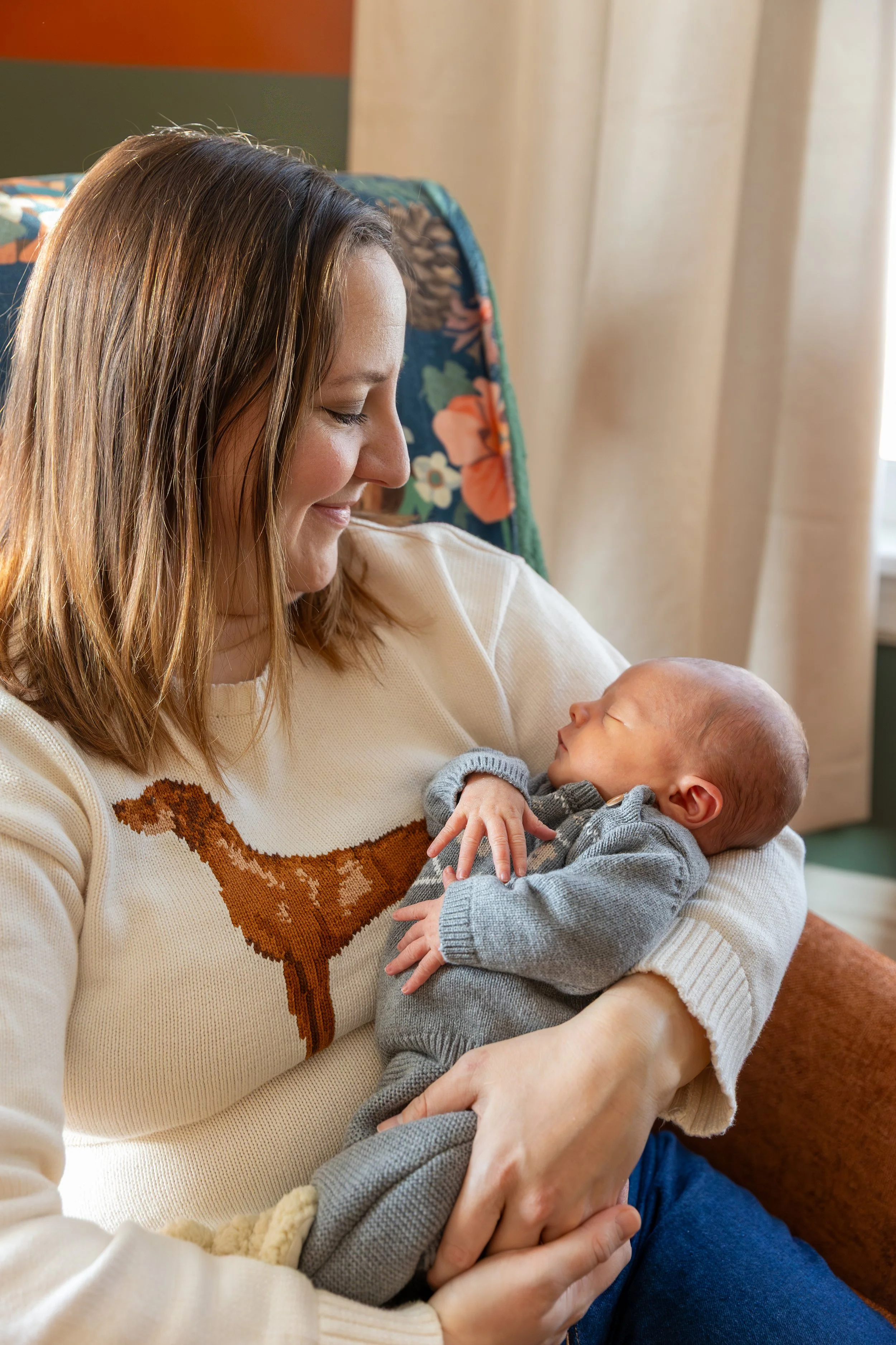 Minneapolis in-home newborn photography session - Mom holds her baby in her arms as she smiles down at the baby.