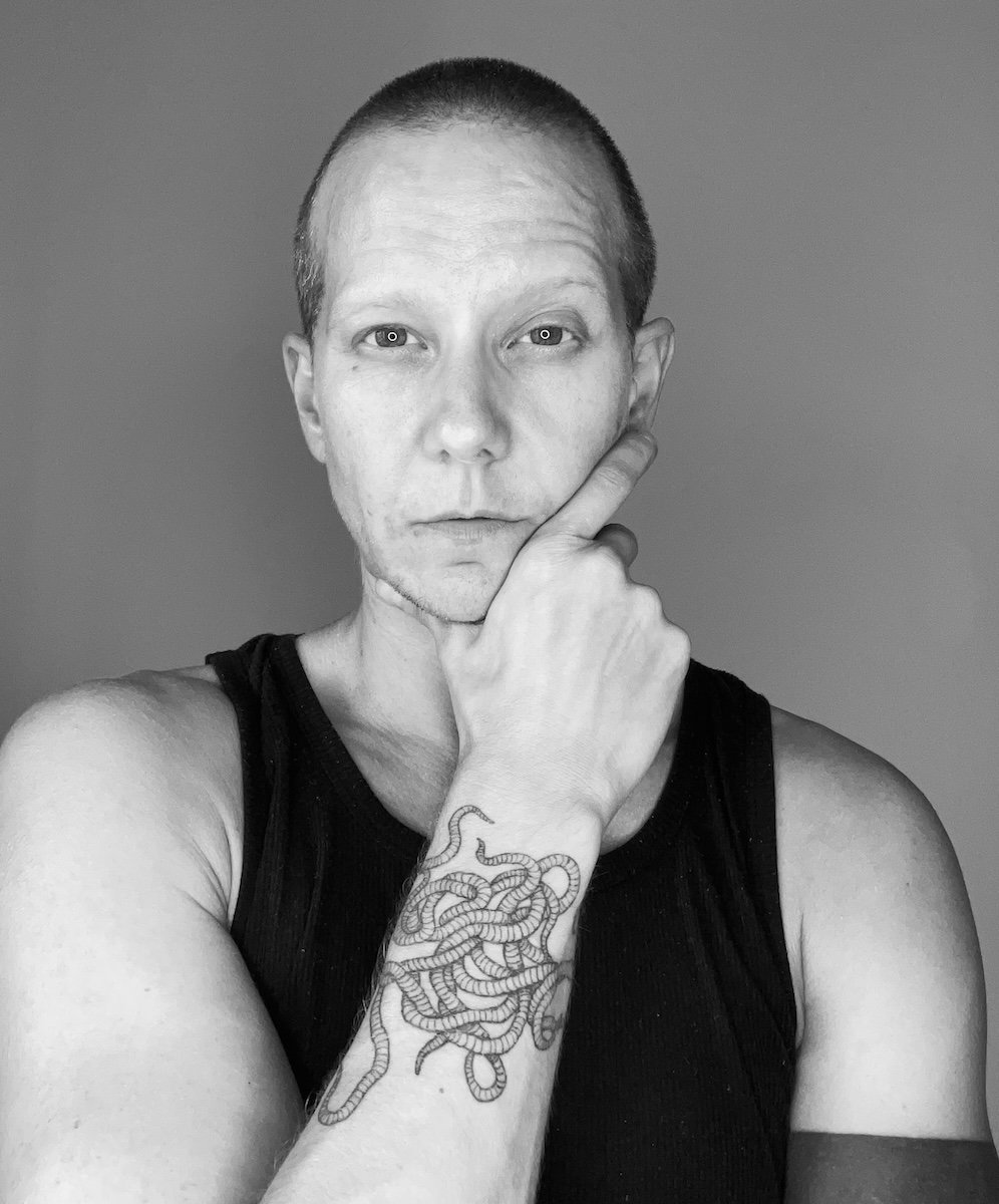 Person with a shaved head wearing a tank.