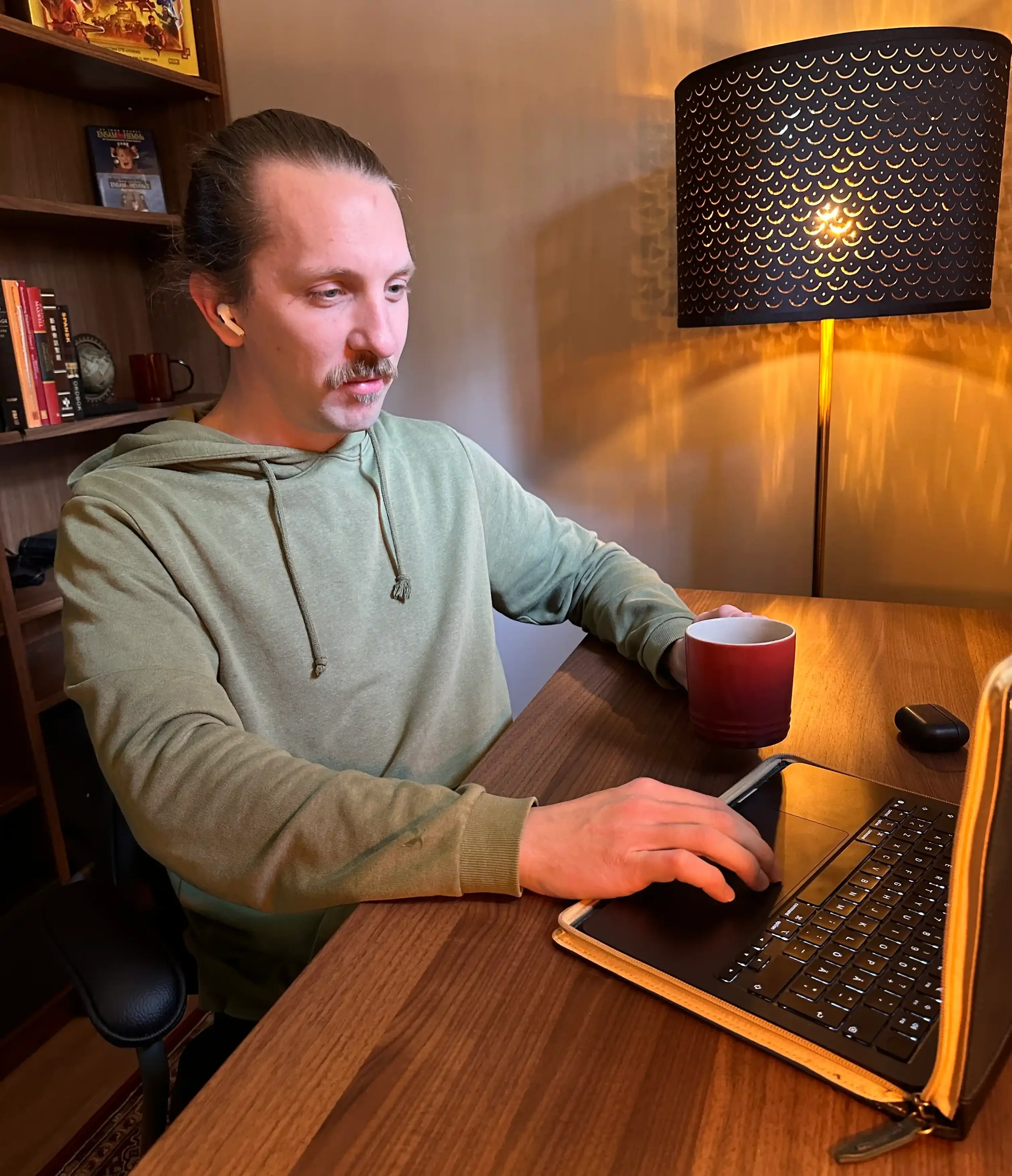 Christian Tapper, founder of Lingtuitive, studying a language at his home-office desk with coffee and earbuds.