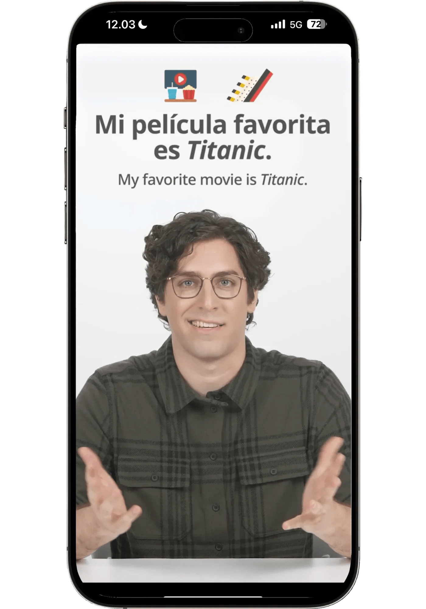 Speak Spanish video lesson showing the phrase "Mi película favorita es Titanic." with the English translation "My favorite movie is Titanic." taught by a bilingual instructor in a green flannel shirt gesturing warmly.