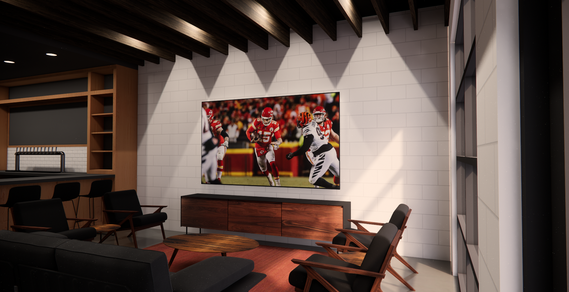 Living room with a large flat screen TV showing a football game, surrounded by black armchairs and wooden furniture, with a white brick wall and wooden ceiling beams.