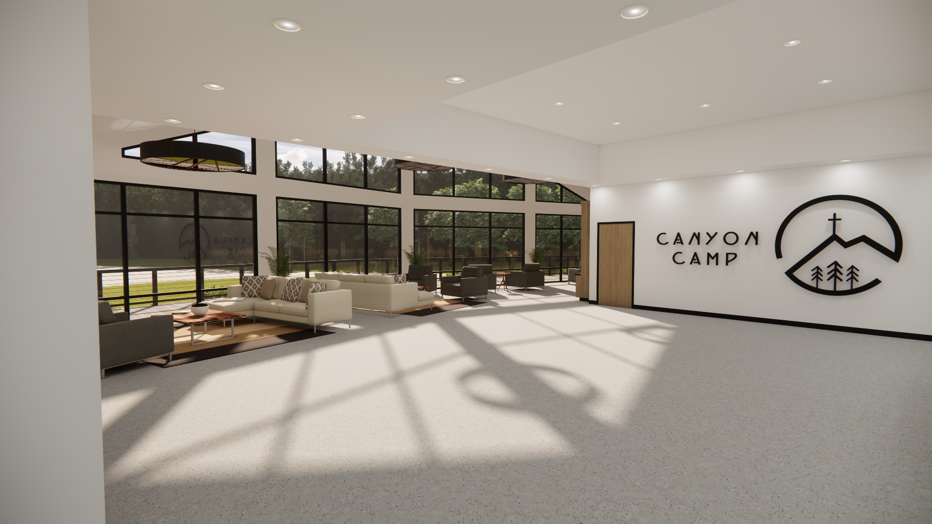 Indoor lounge area at Canyon Camp with white and black furniture, large windows, and a logo on the wall featuring mountains, trees, and a cross.