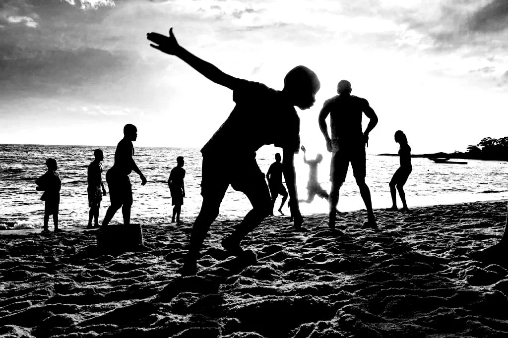 Silhouettes of people playing and enjoying activities on the beach during sunset