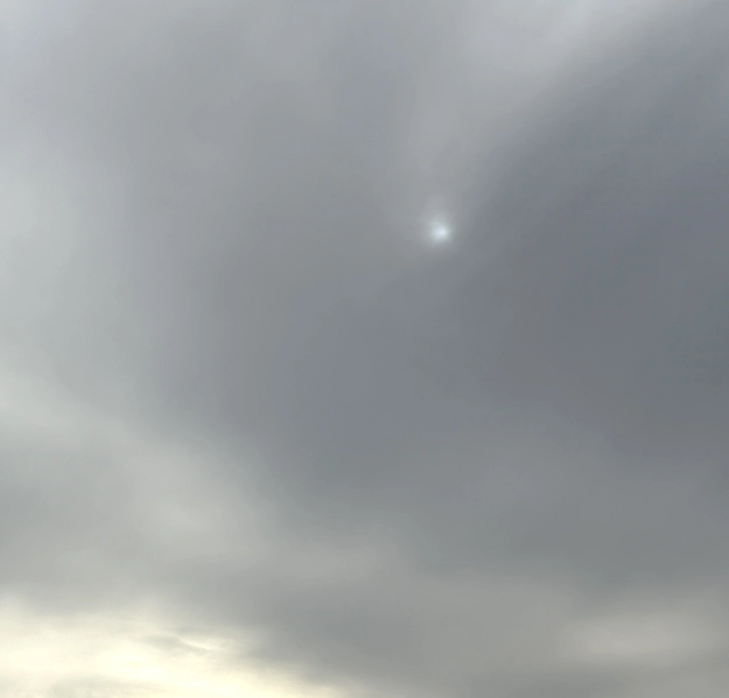 Overcast sky with thick gray clouds and a faint, almost hidden, sun.
