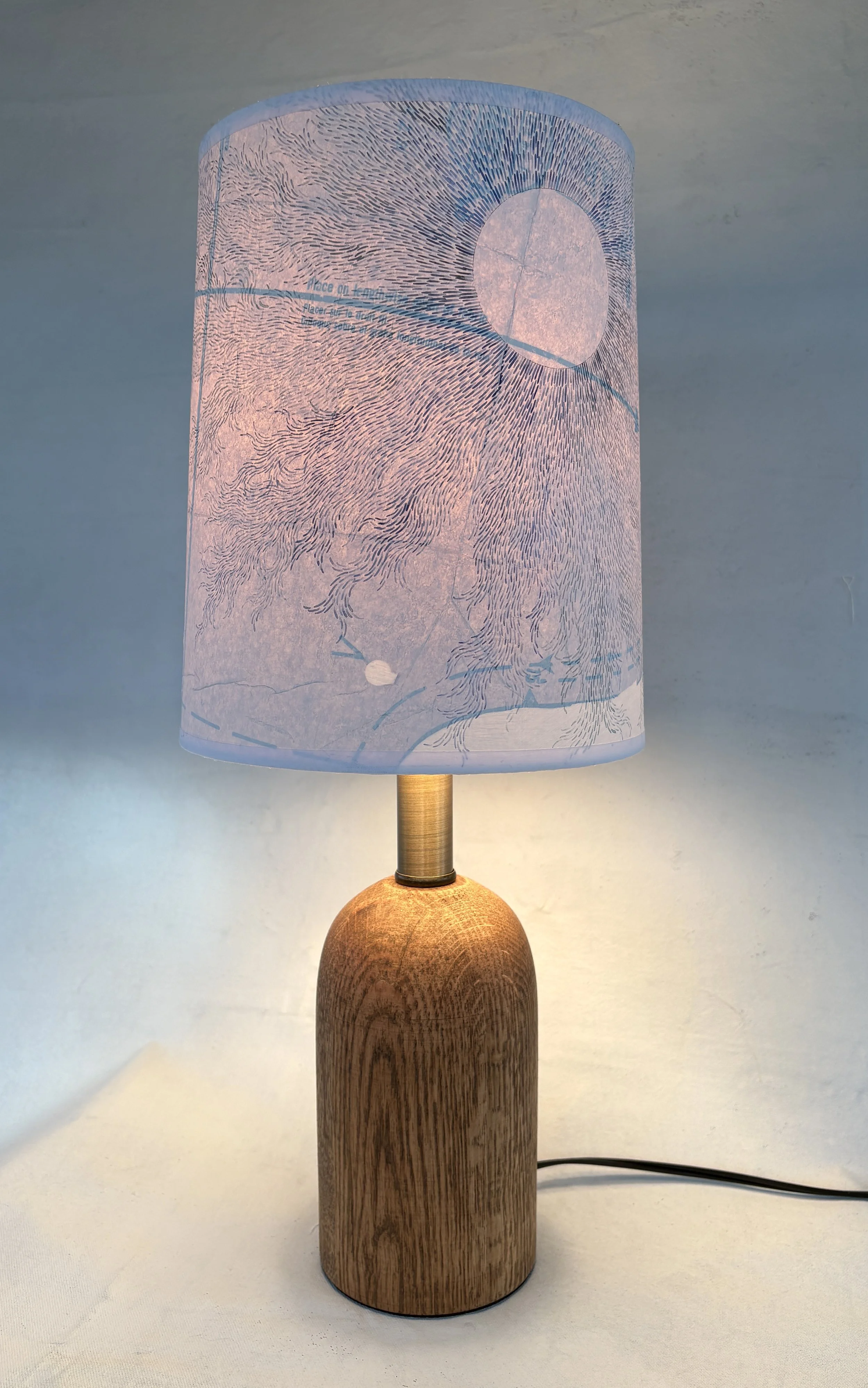 Decorative table lamp with a wooden base and a handpainted lampshade featuring a delicate, abstract line art design resembling flowing water.