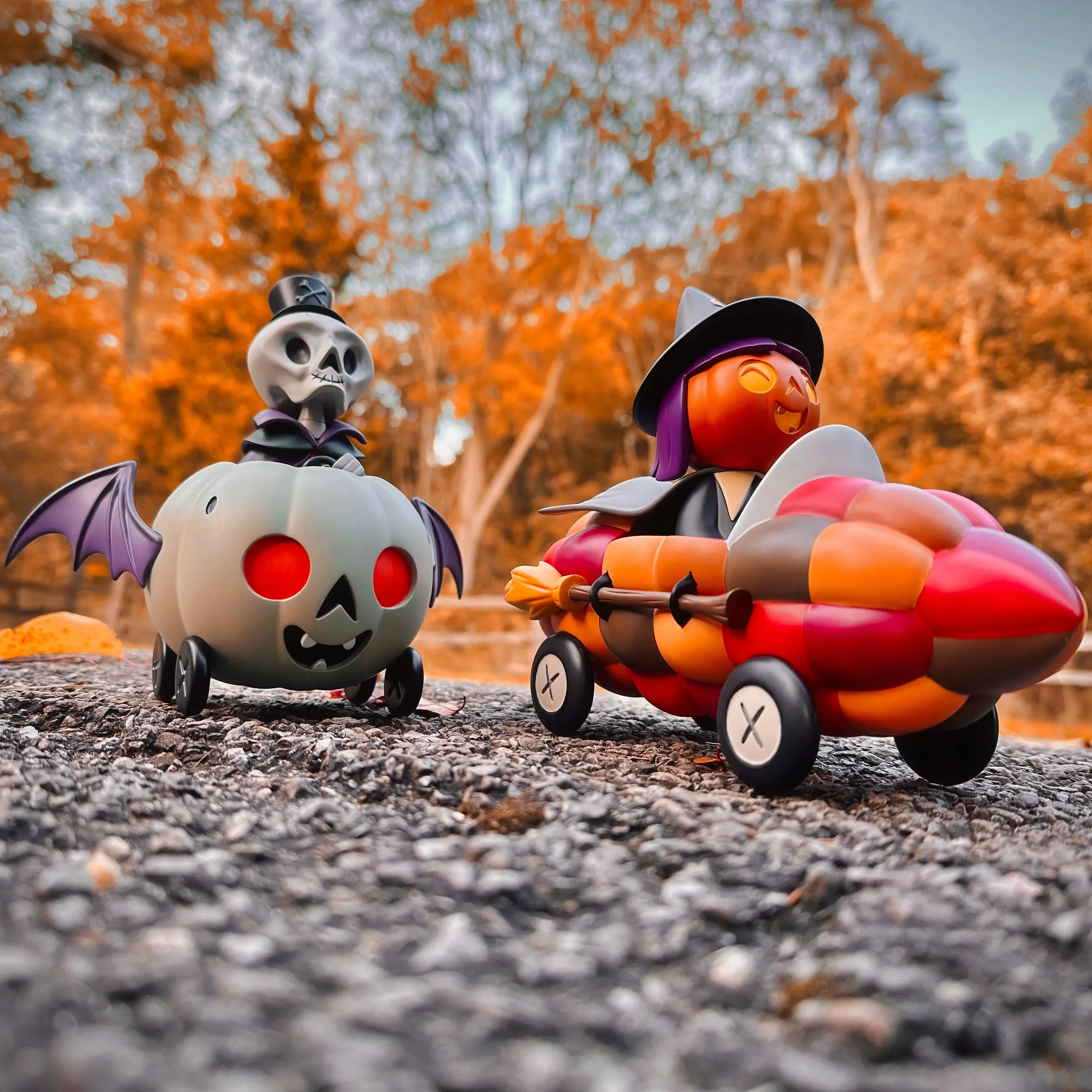 Stephanie Buscema Corny Cruisers resin art toys: Nigel the Necromancer and Willa the Way-Out Witch racing on autumn pavement