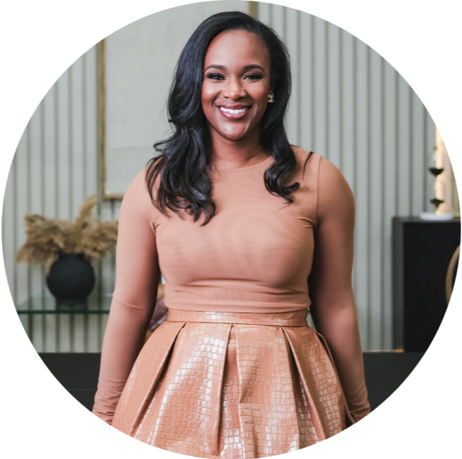 A smiling woman in a beige long-sleeve top and a metallic tan skirt standing in a room with modern decor.
