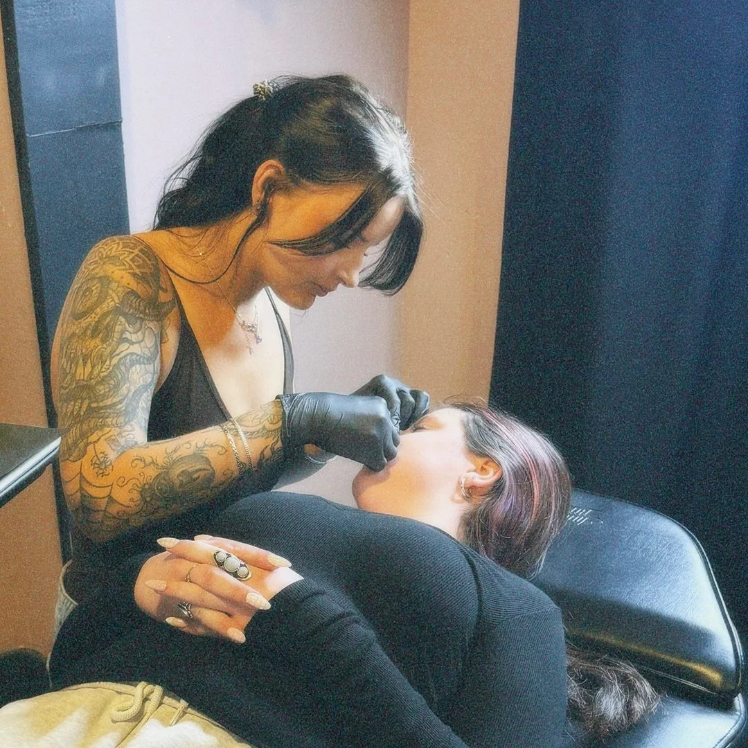 Portrait of Love Dove Tattoo's resident piercer Erin performing a nostril piercing on a client