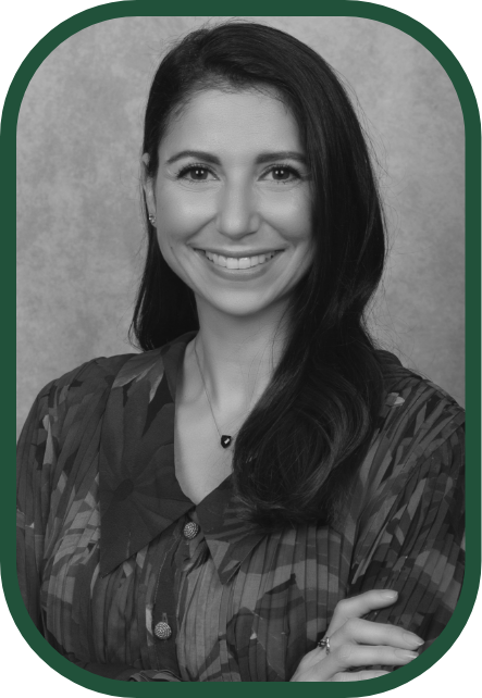 A smiling woman with long dark hair, wearing a patterned blouse, against a neutral background