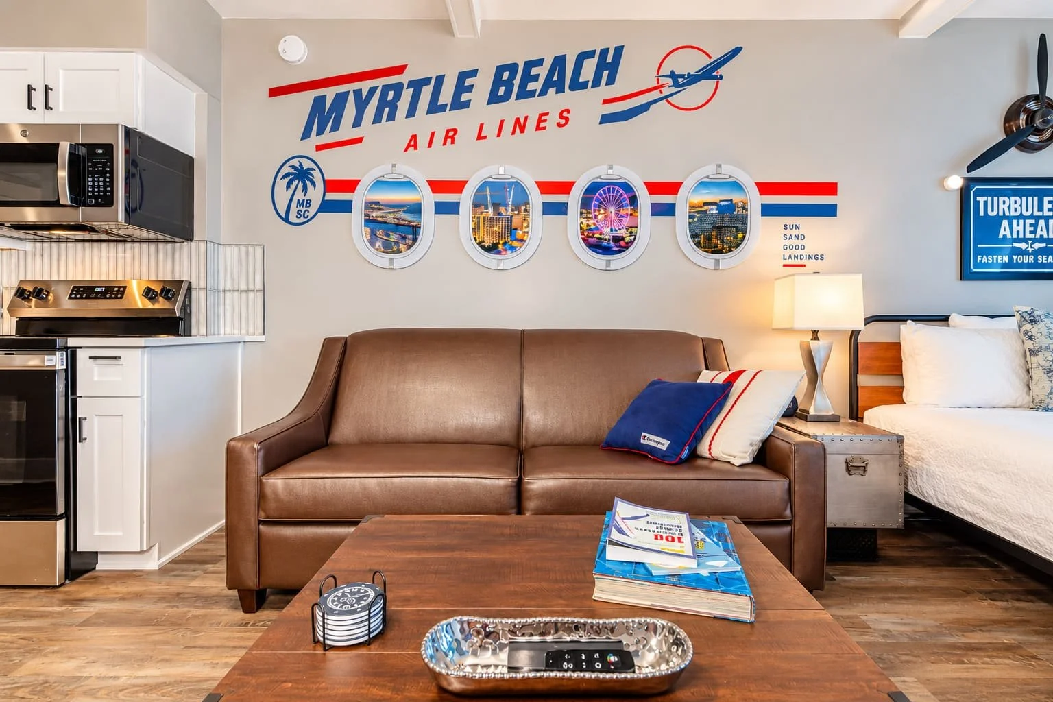 Living room with Myrtle Beach Air Lines decor, including pictures, a couch, a lamp, and a bed.