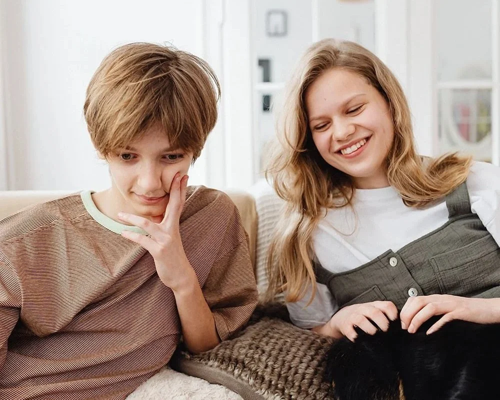 Two teens looking at a laptop together during an online game.